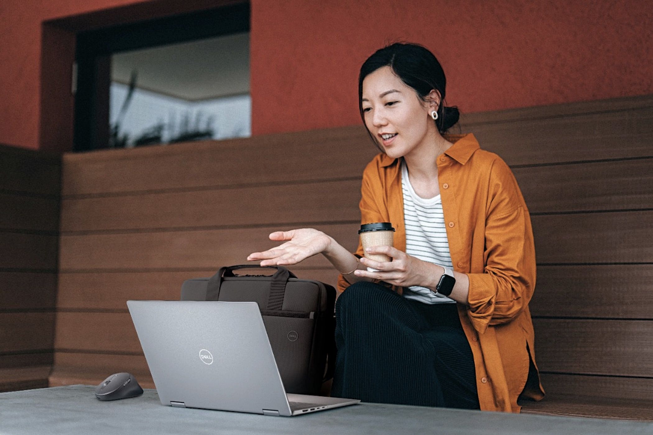 A woman drinking coffee and chatting on her Dell laptop.
