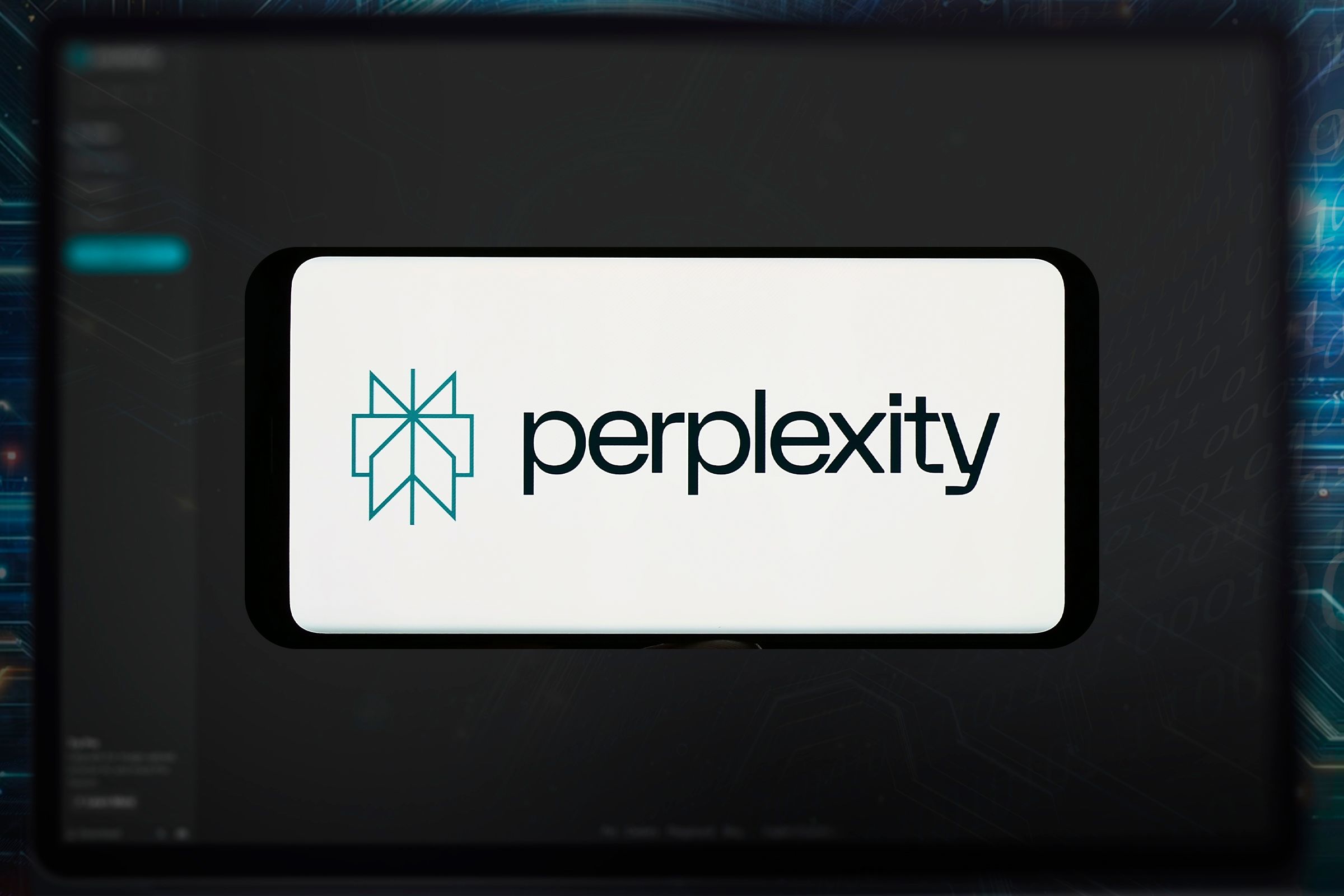 Perplexity AI on a smartphone screen with a notebook screen in the background