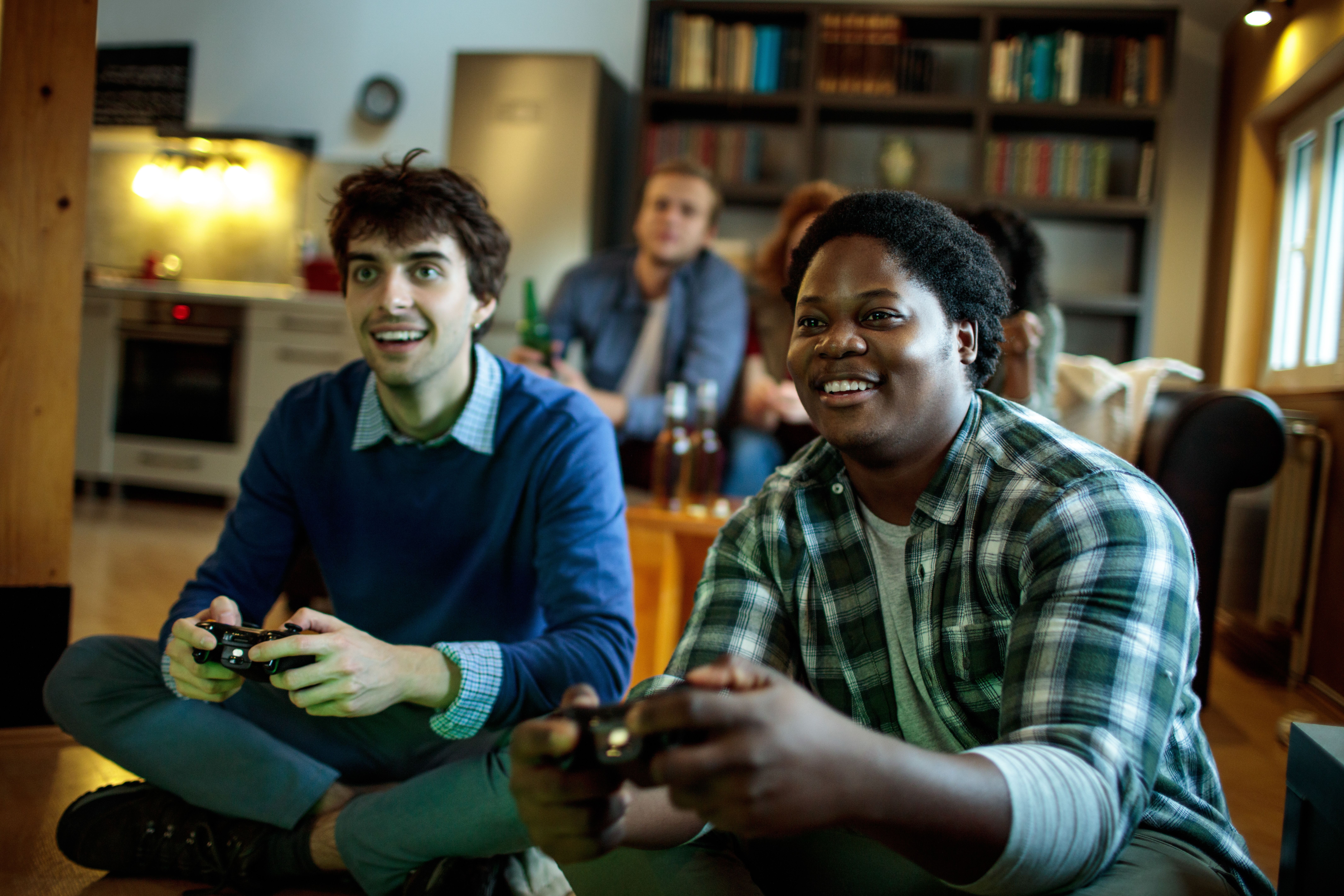 Young people playing local multiplayer video games in the living room on a gaming console.