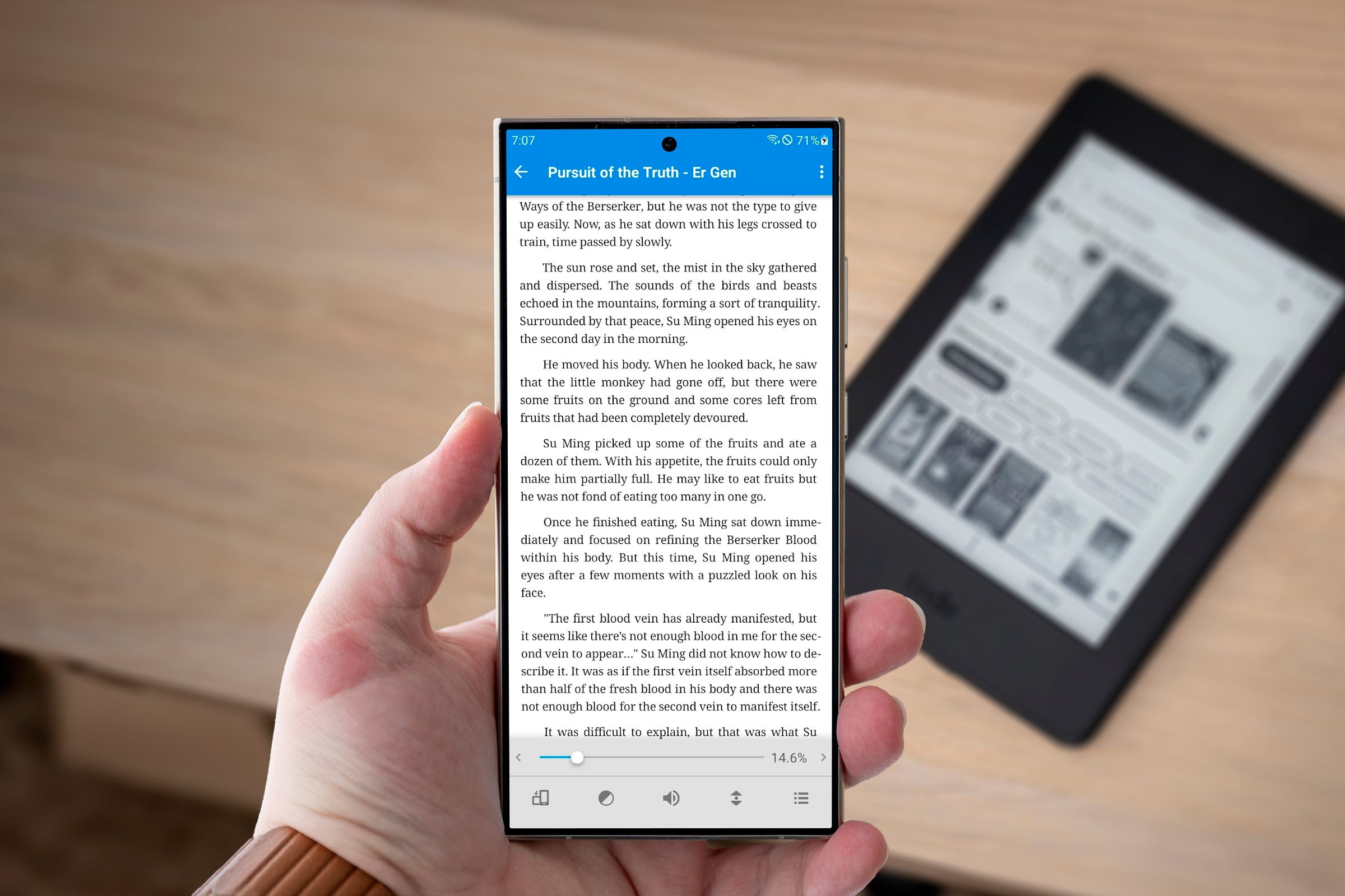 An ebook on a cellphone screen with a blurred Kindle in the background.