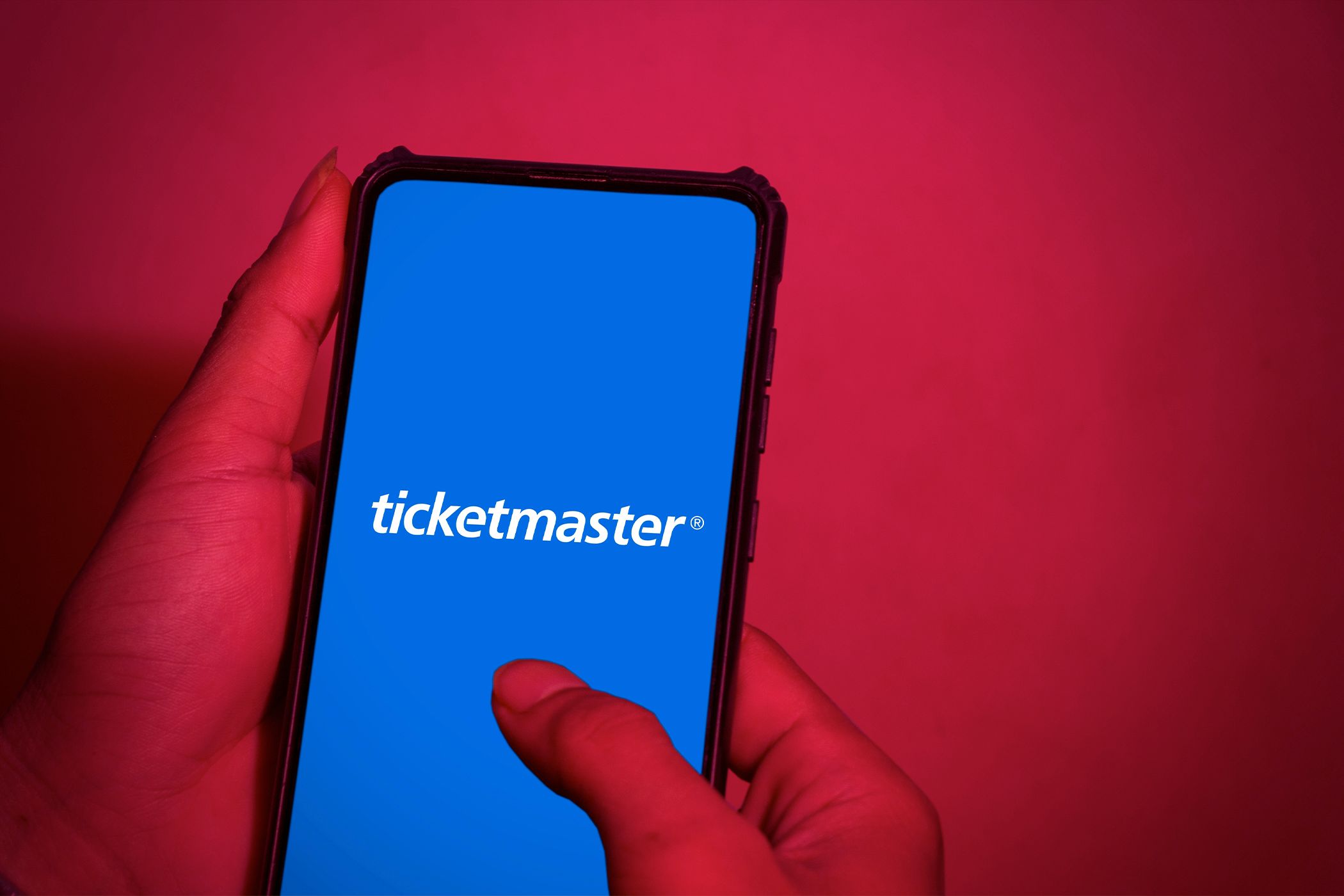 The Ticketmaster logo on a phone with a red background.