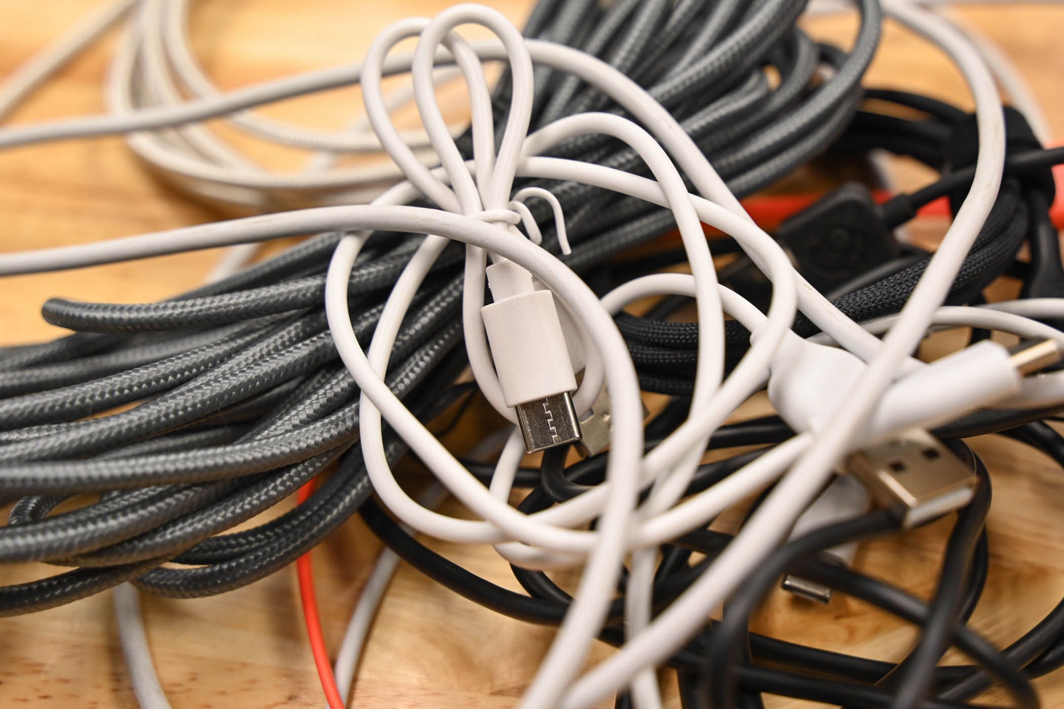 A pile of USB cables on a wood surface.