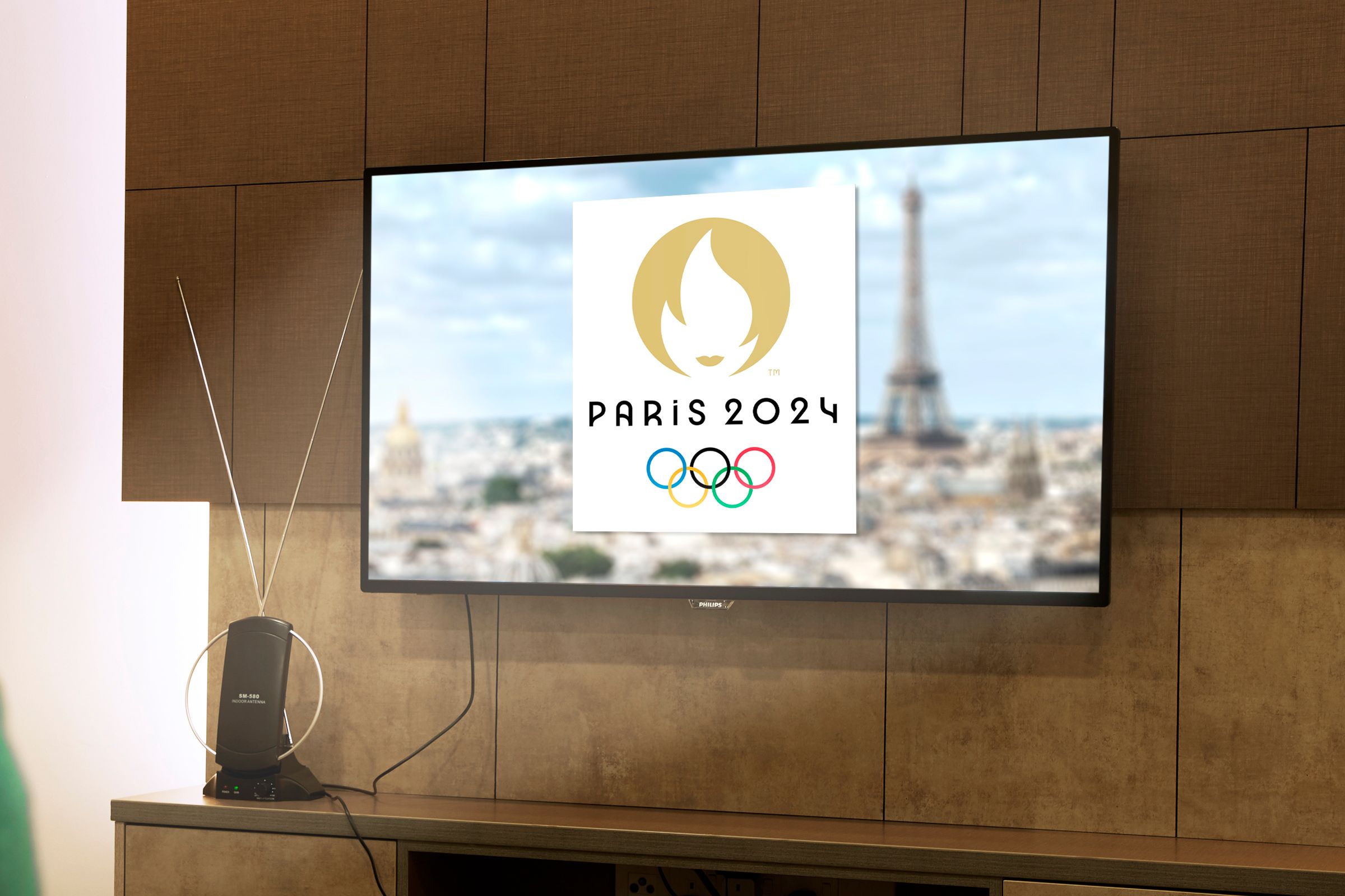 A panel with a TV displaying an image of the 2024 Paris Olympics, and an antenna on the shelf.