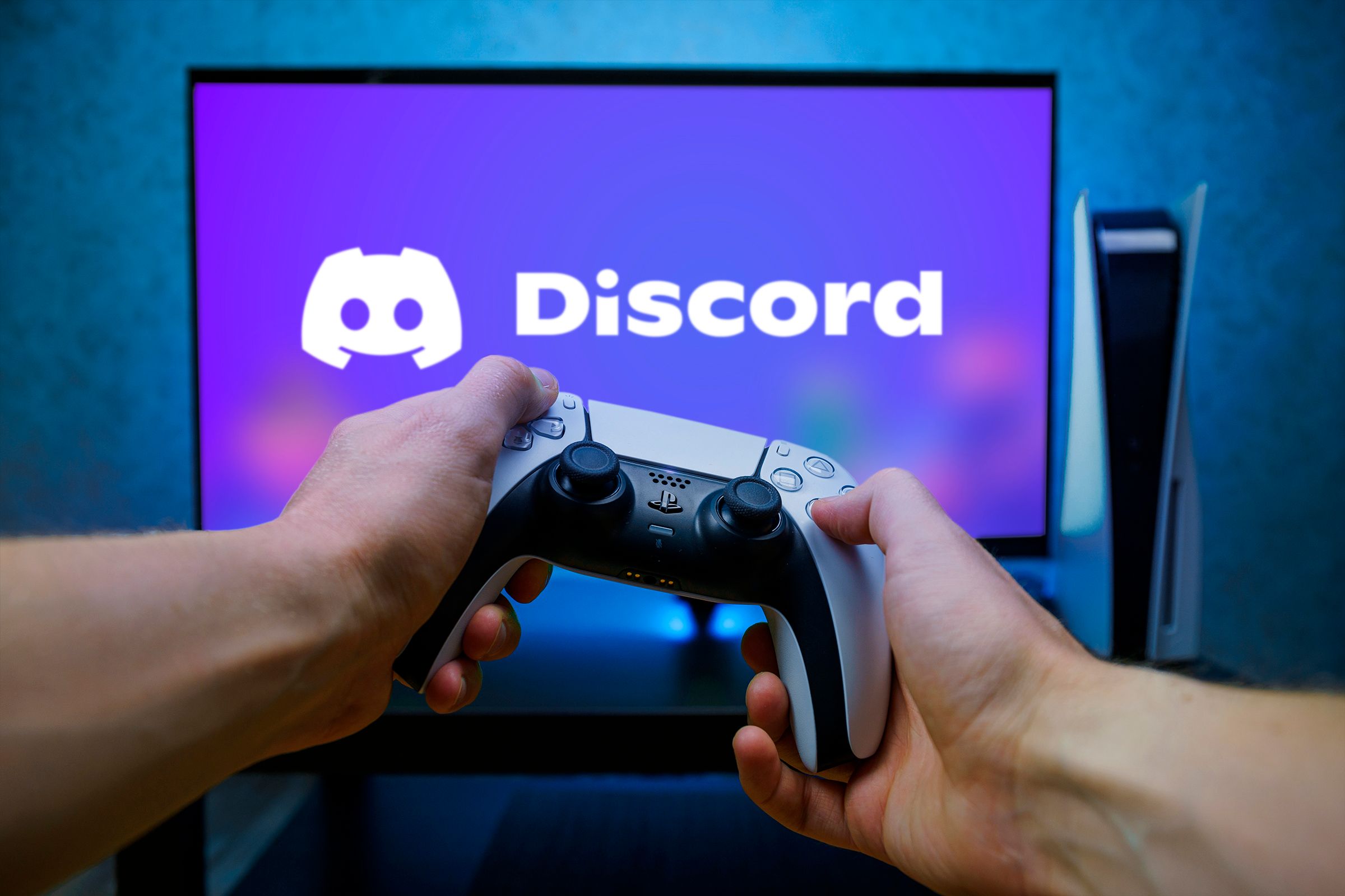 A person holding a PS5 DualSense controller and a TV in front with the Discord logo.
