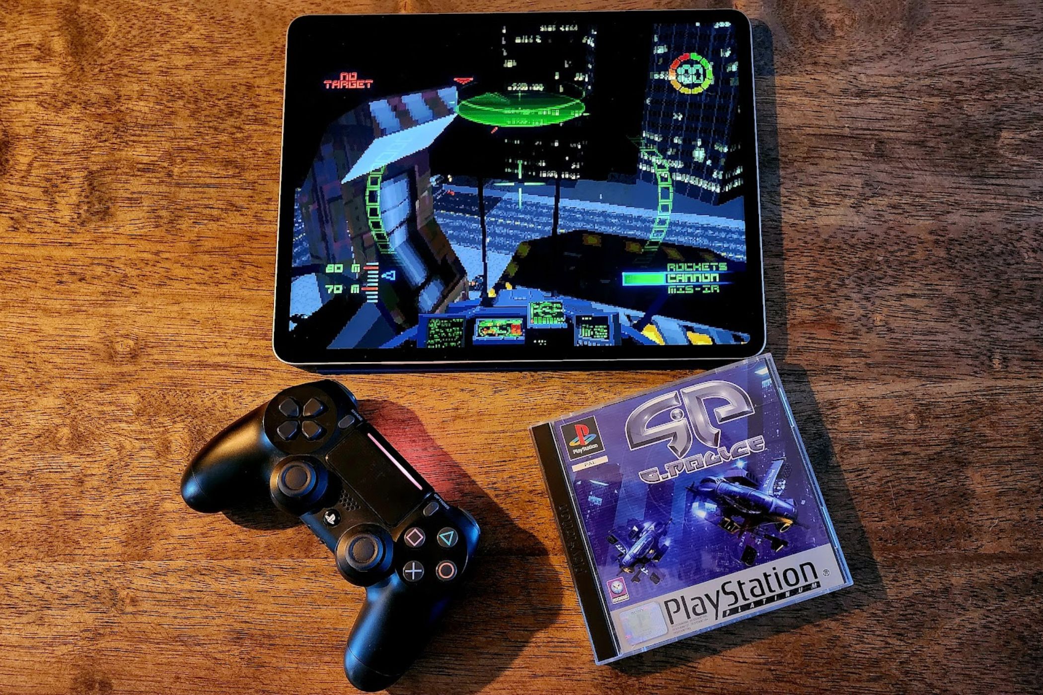An iPad running G-Police next a  physical original copy of the game and a PS4 controller