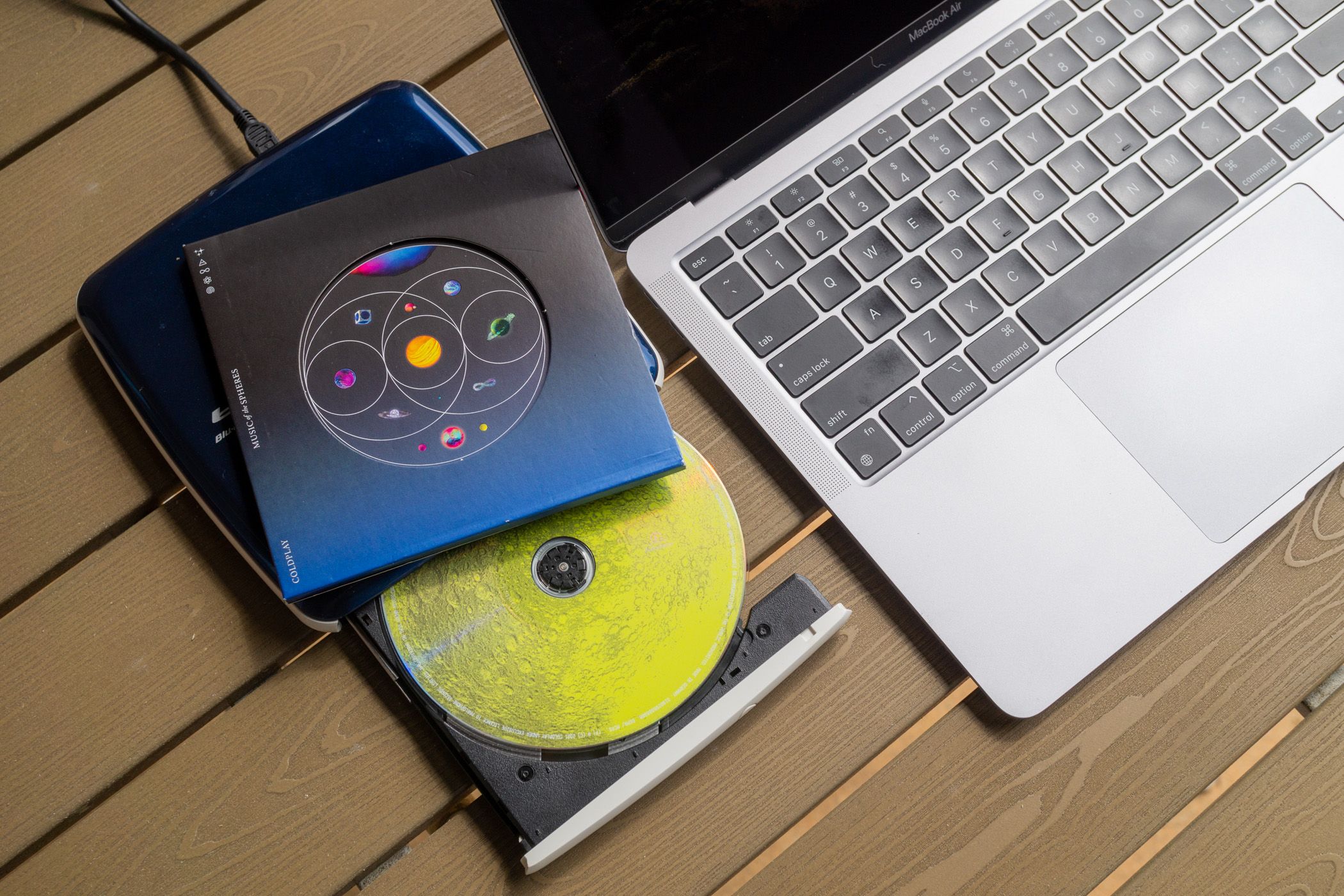 CD drive and a music CD next to a MacBook Air.