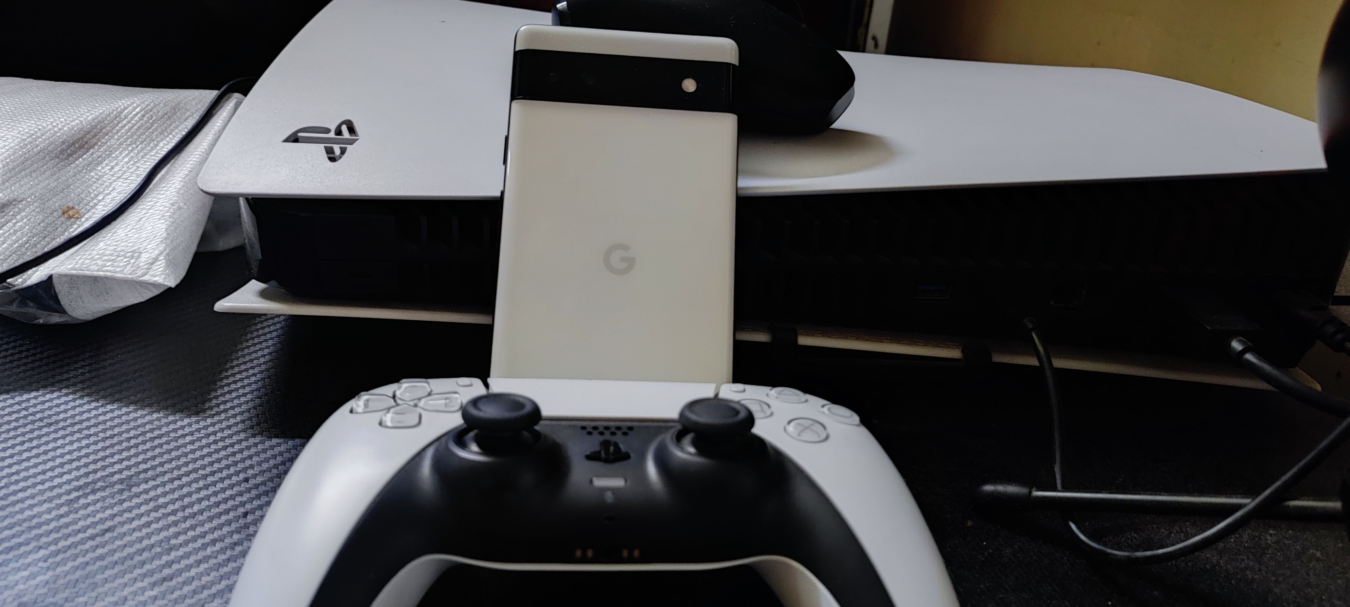 Pixel 6a in front of the PS5 exhaust supported by a PS5 controller