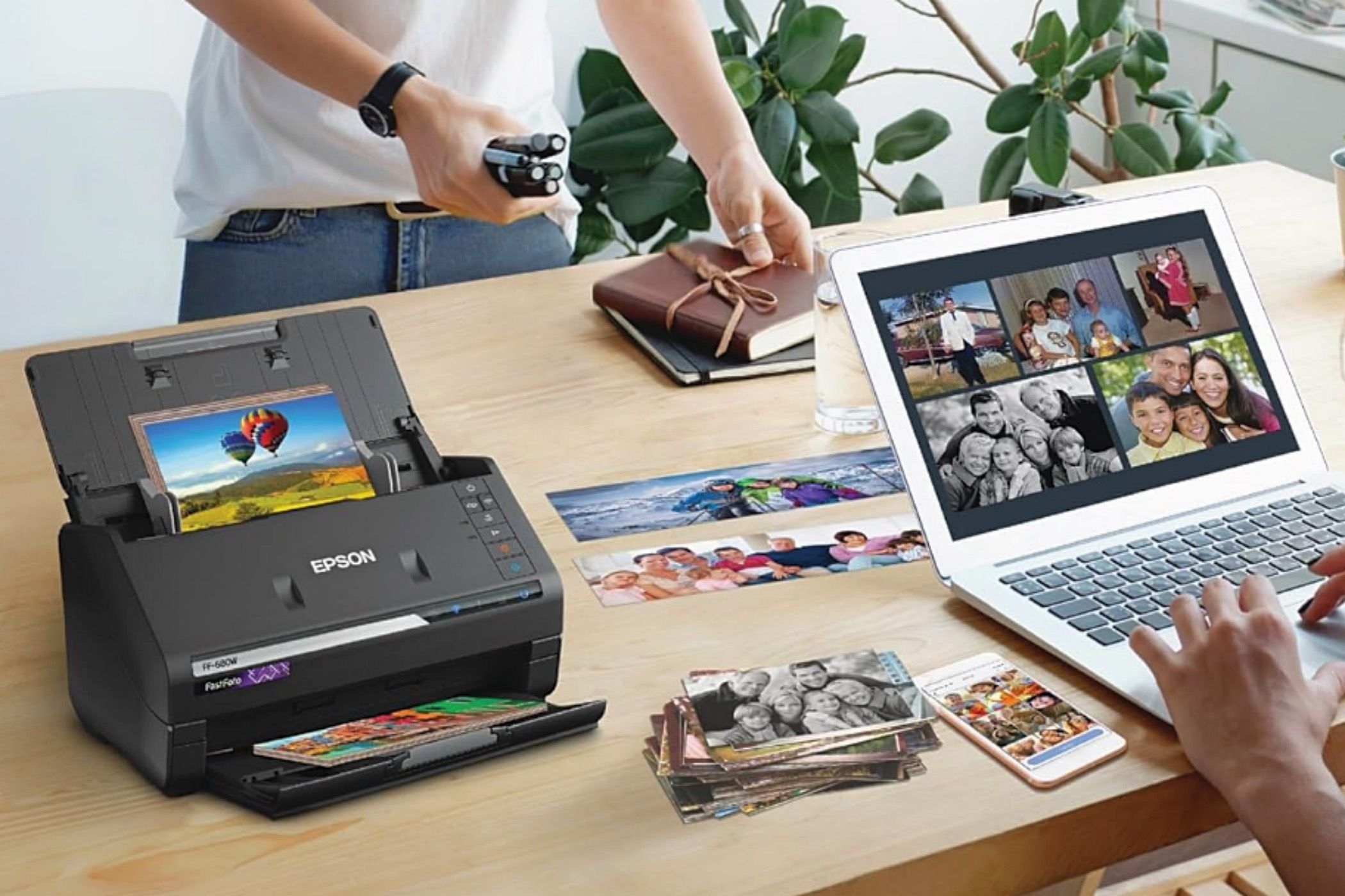 A FastFoto FF-680W on the desk next to a woman using her laptop