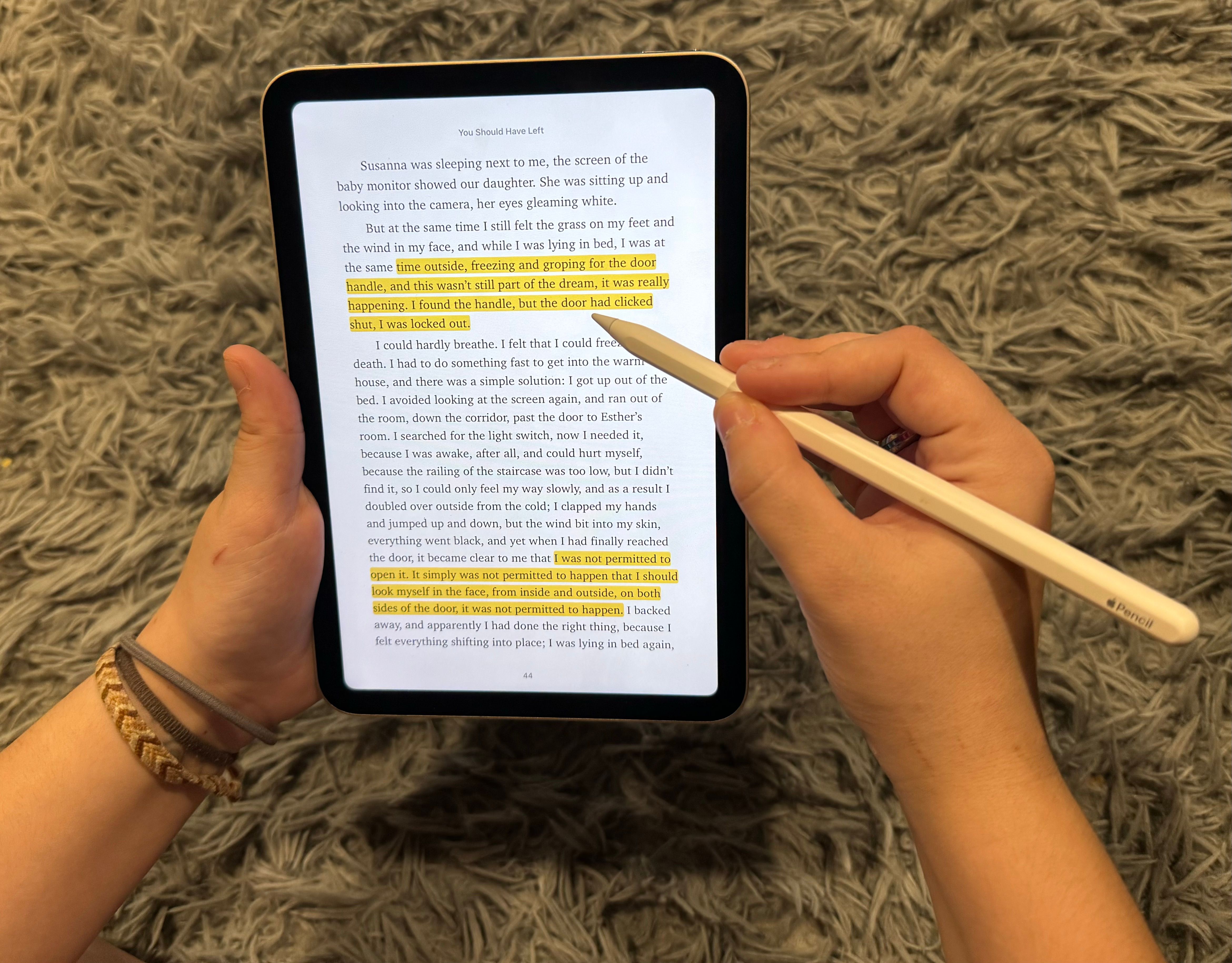 Person holding an iPad mini reading a book, highlighting passages. 