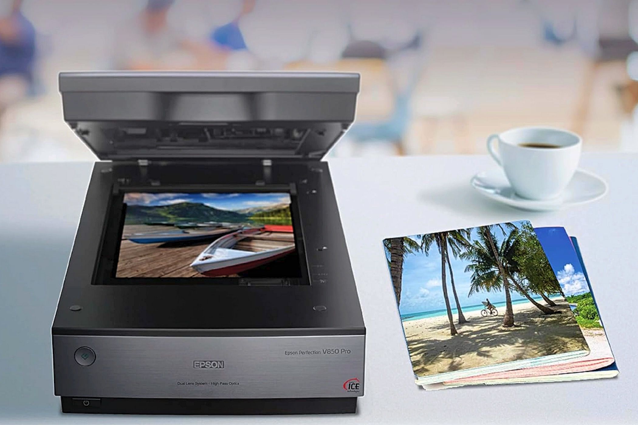 An Epson Perfection V850 Pro next to some photos and a cup of coffee