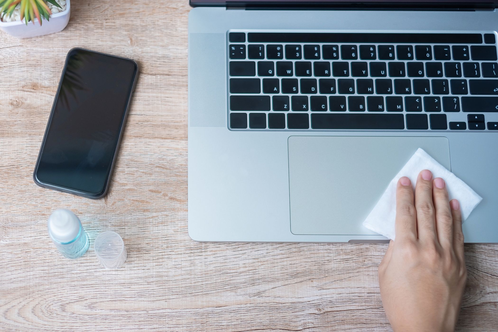 Woman's hand cleaning laptop and smartphone by wet wipes tissue and alcohol disinfectant.