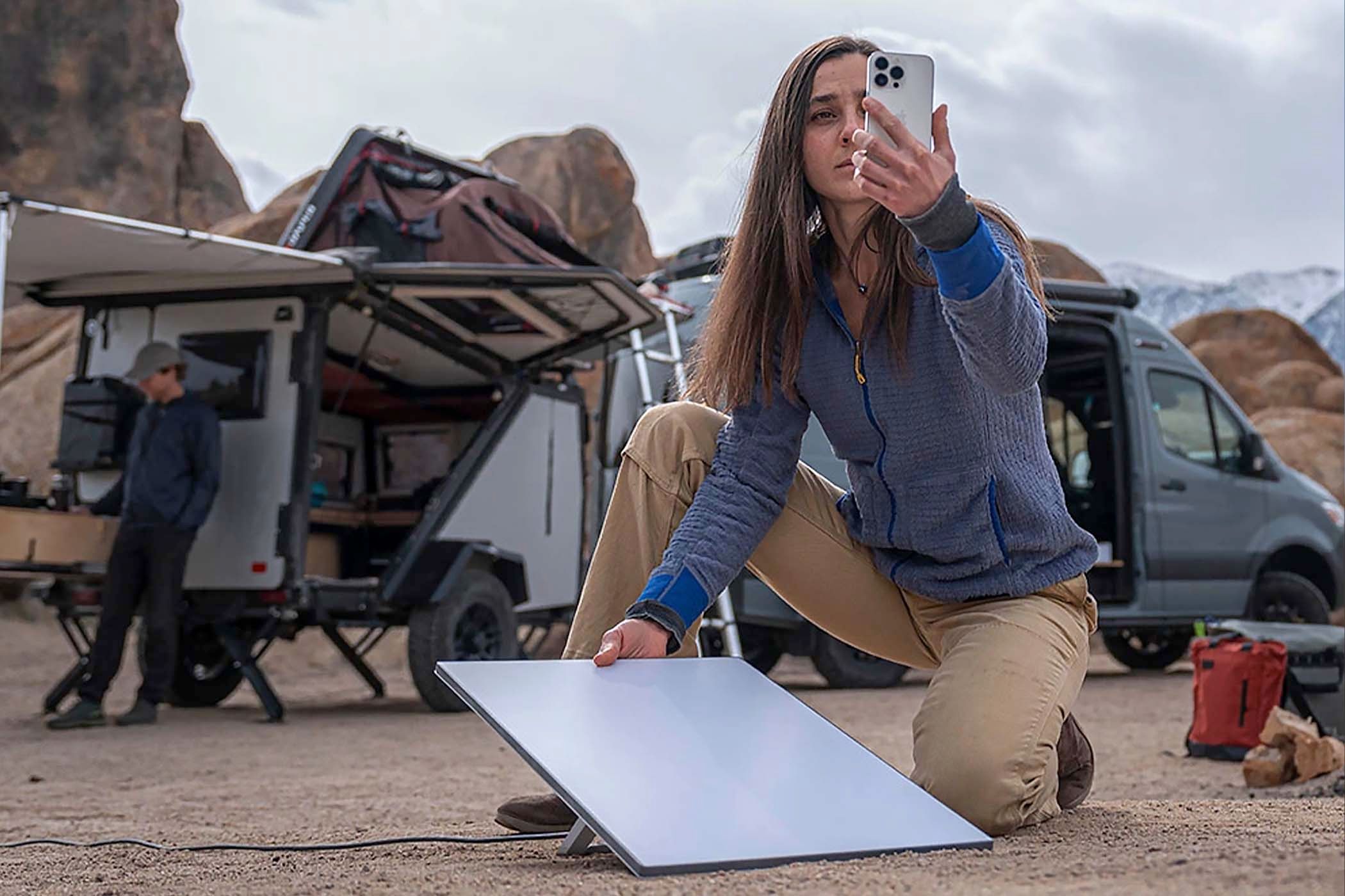 A woman setting up the Starlink Mini in a remote desert near a truck.