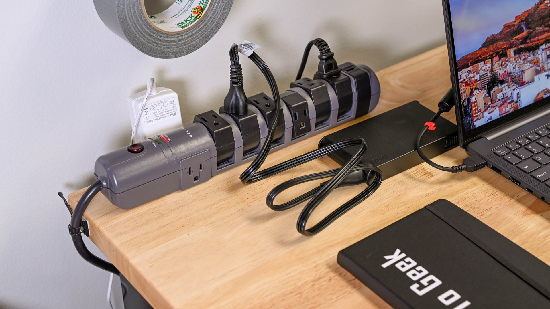 A Belkin surge protector on a workbench with cables plugged into it