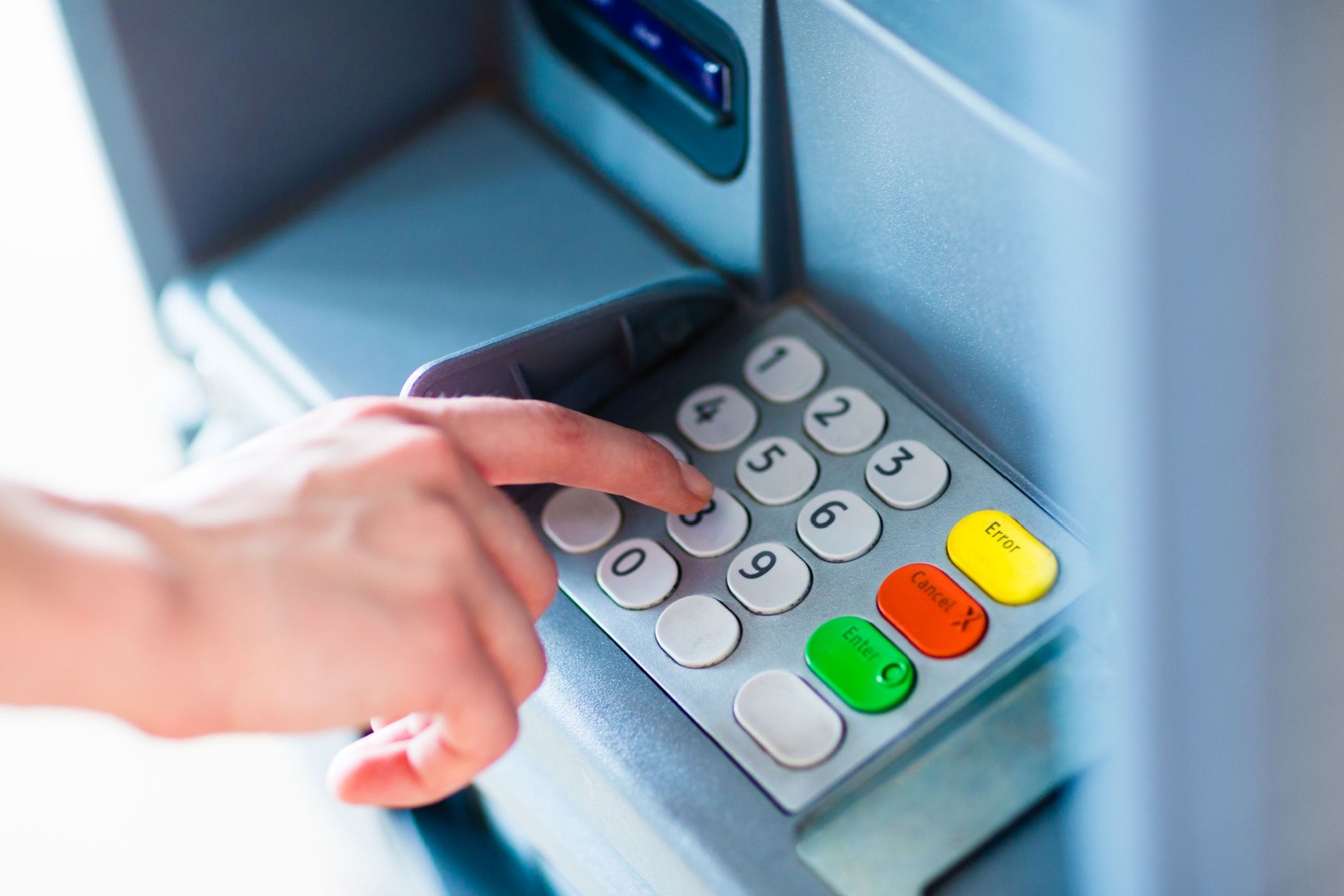 Close-up of hand entering PIN:pass code on ATM:bank machine keypad