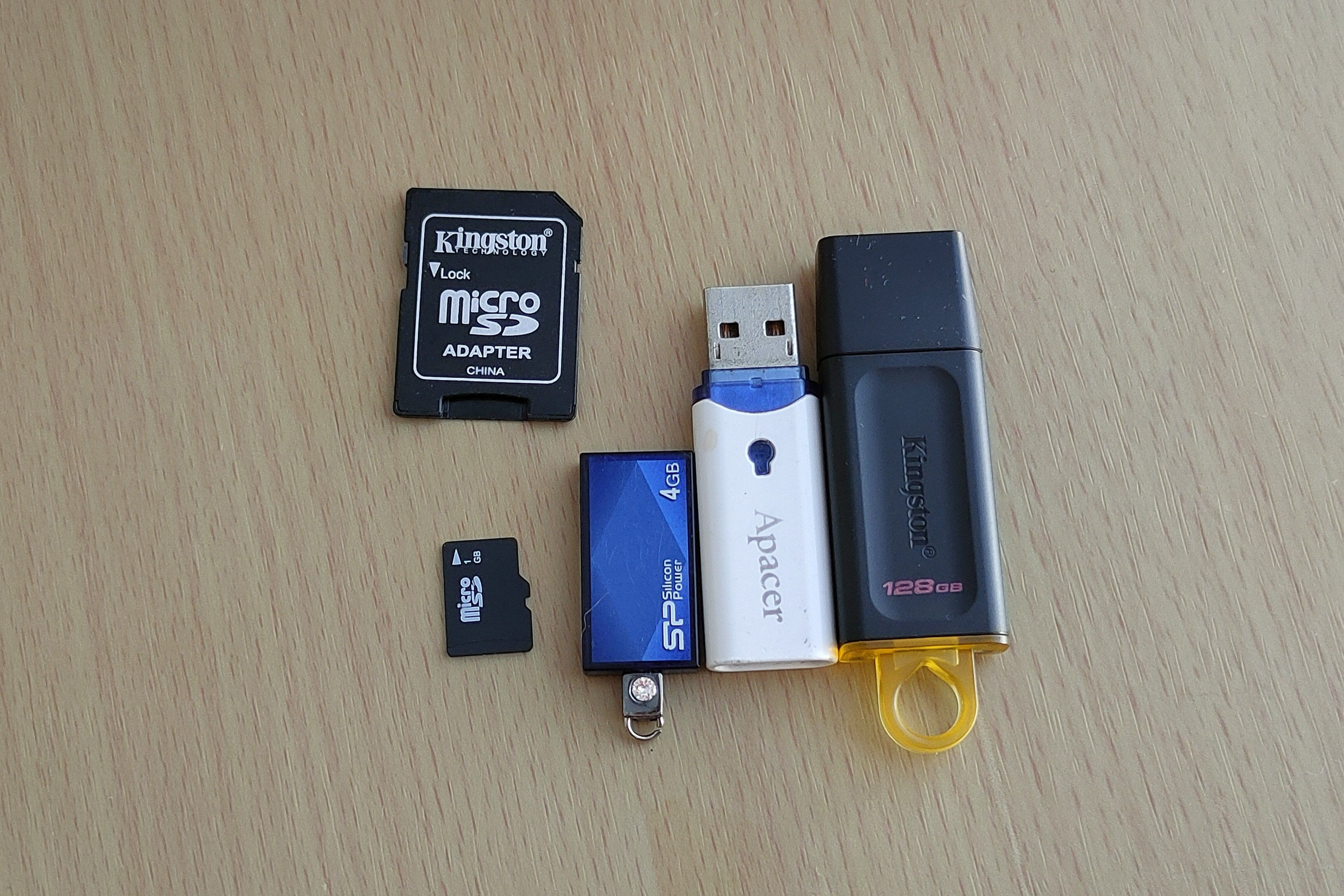A microSD card and SD card adapter next to three different USB flash drives.