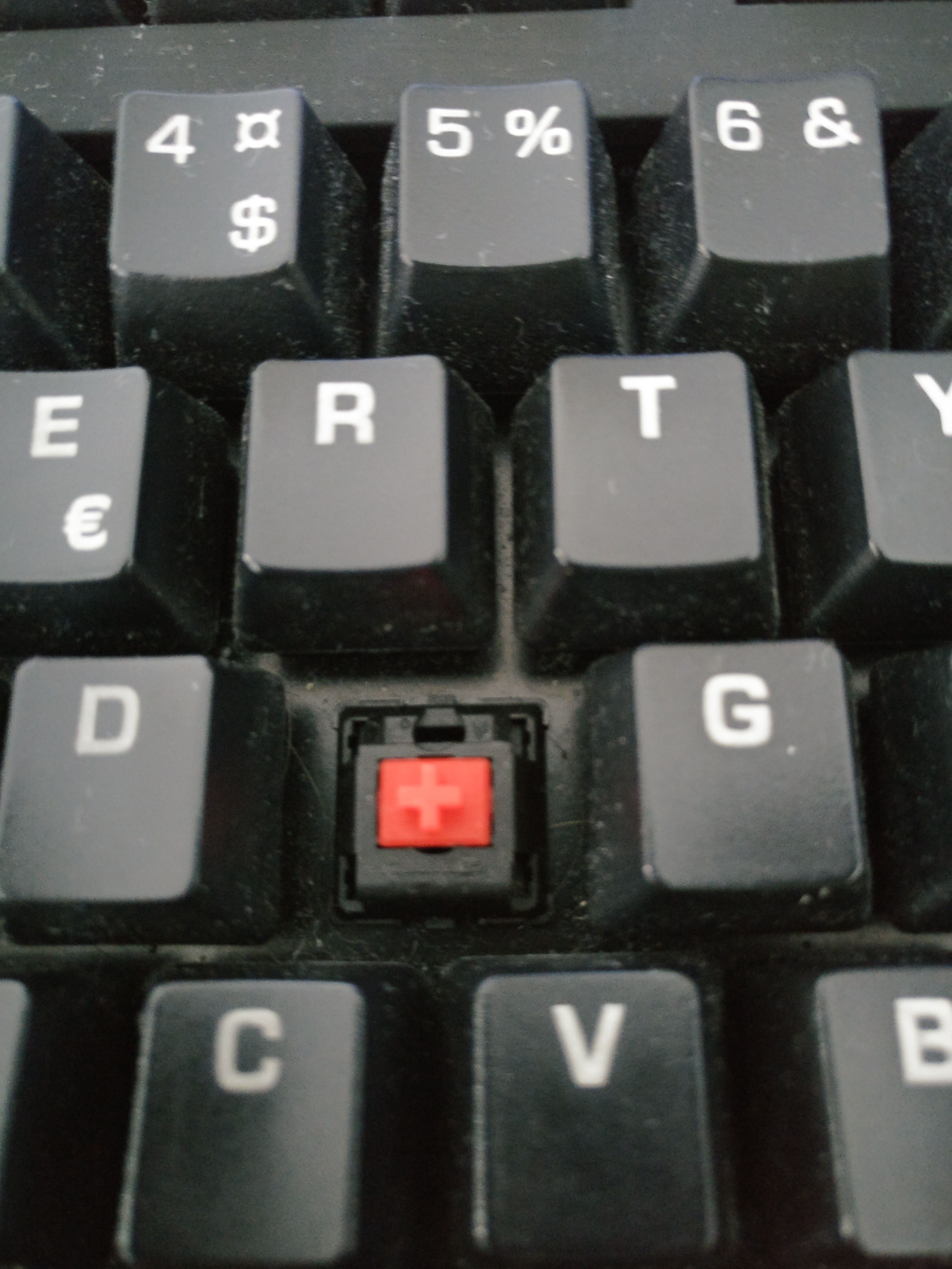 A Cherry MX Red switch inside of a dirty computer keyboard.