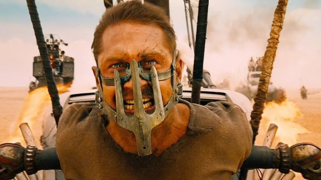 Mad Max Fury Road promo image showing Max tied to a vehicle, wearing a makeshift mask.