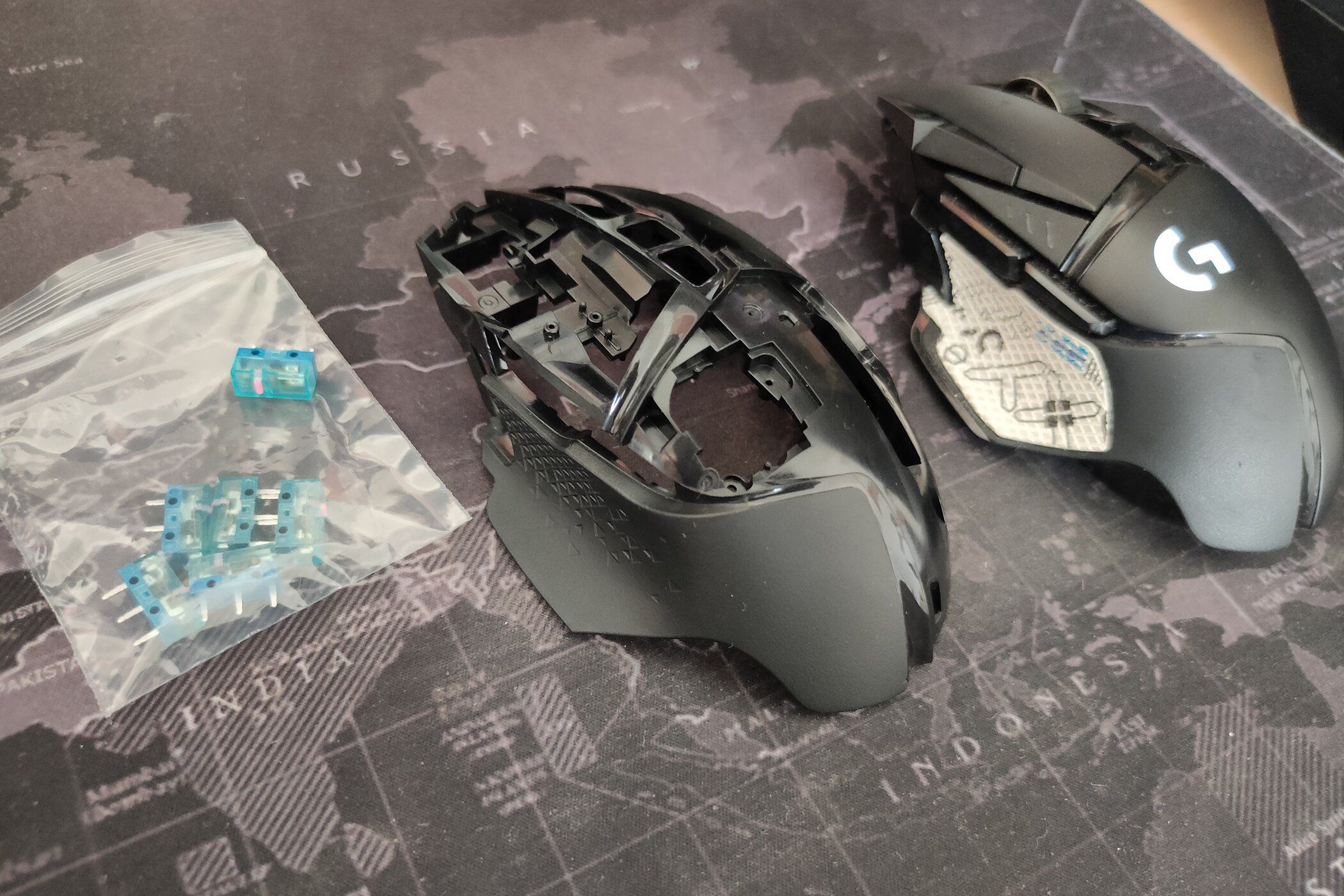 The Logitech G502 Lightspeed next to a replacement plastic shell and some mouse microswitches.