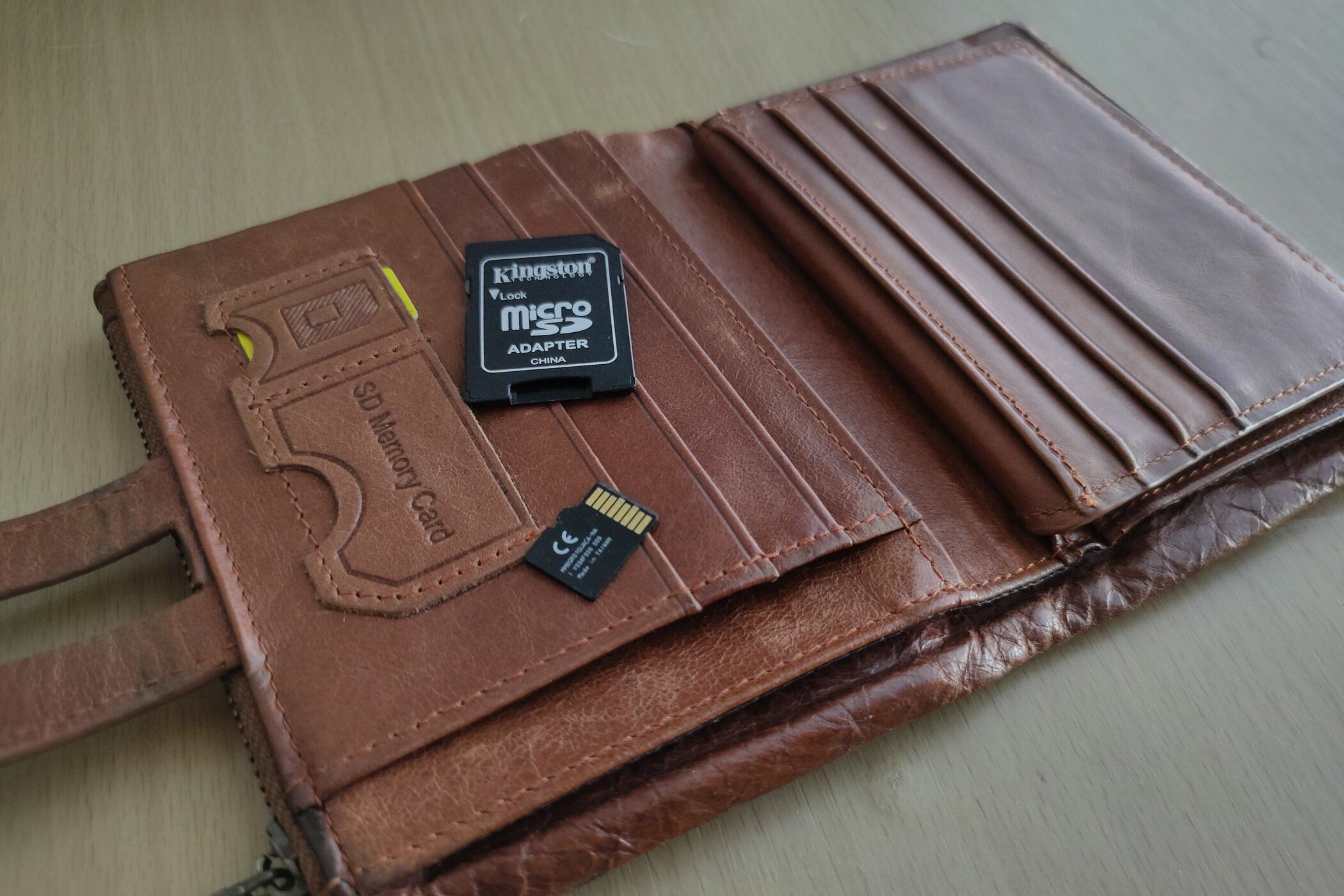 A microSD card and SD card adapter placed on a brown leather wallet.