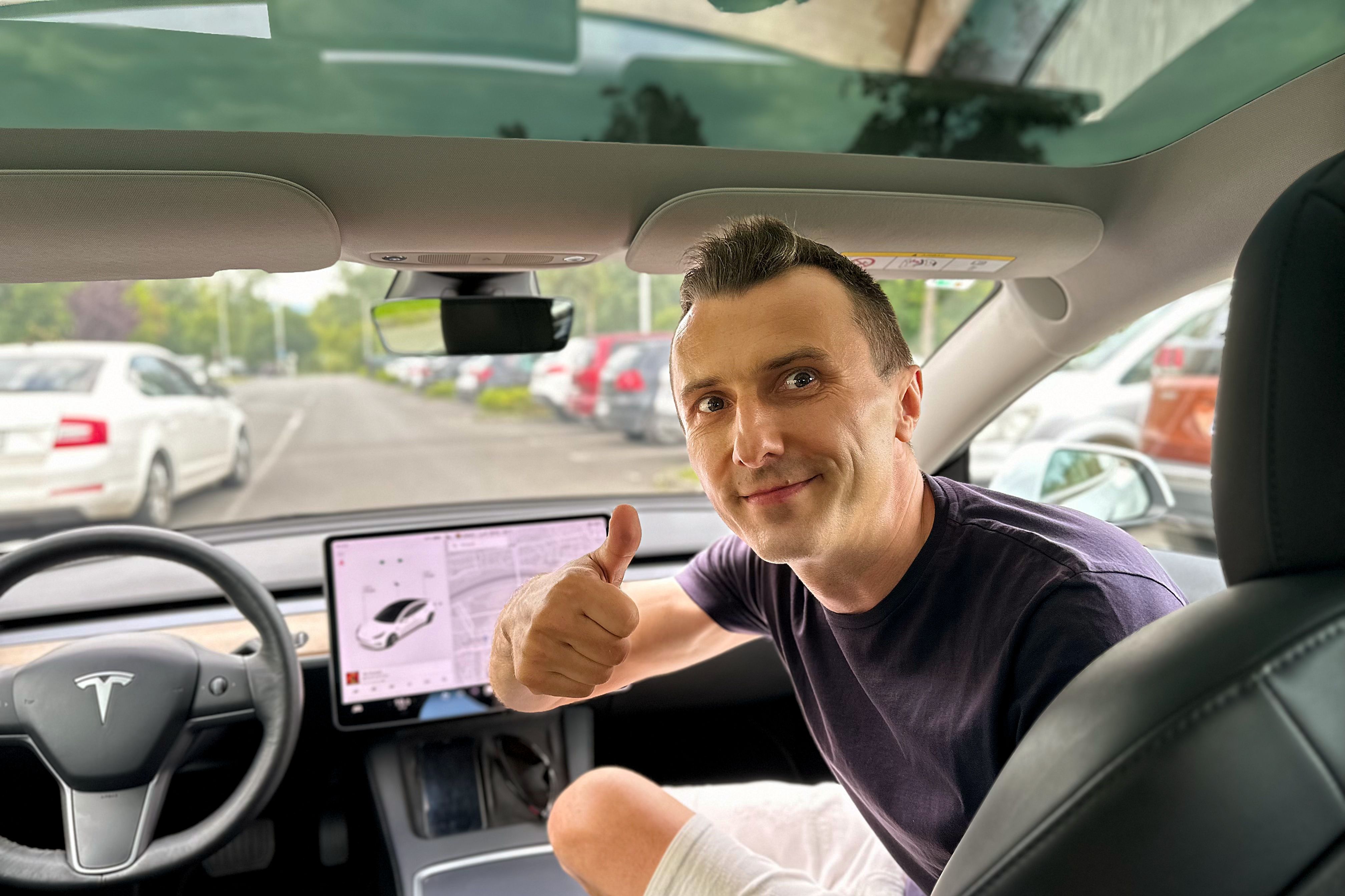 A person in a Tesla passenger seat high-fiving at the camera, shot from the rear seat.