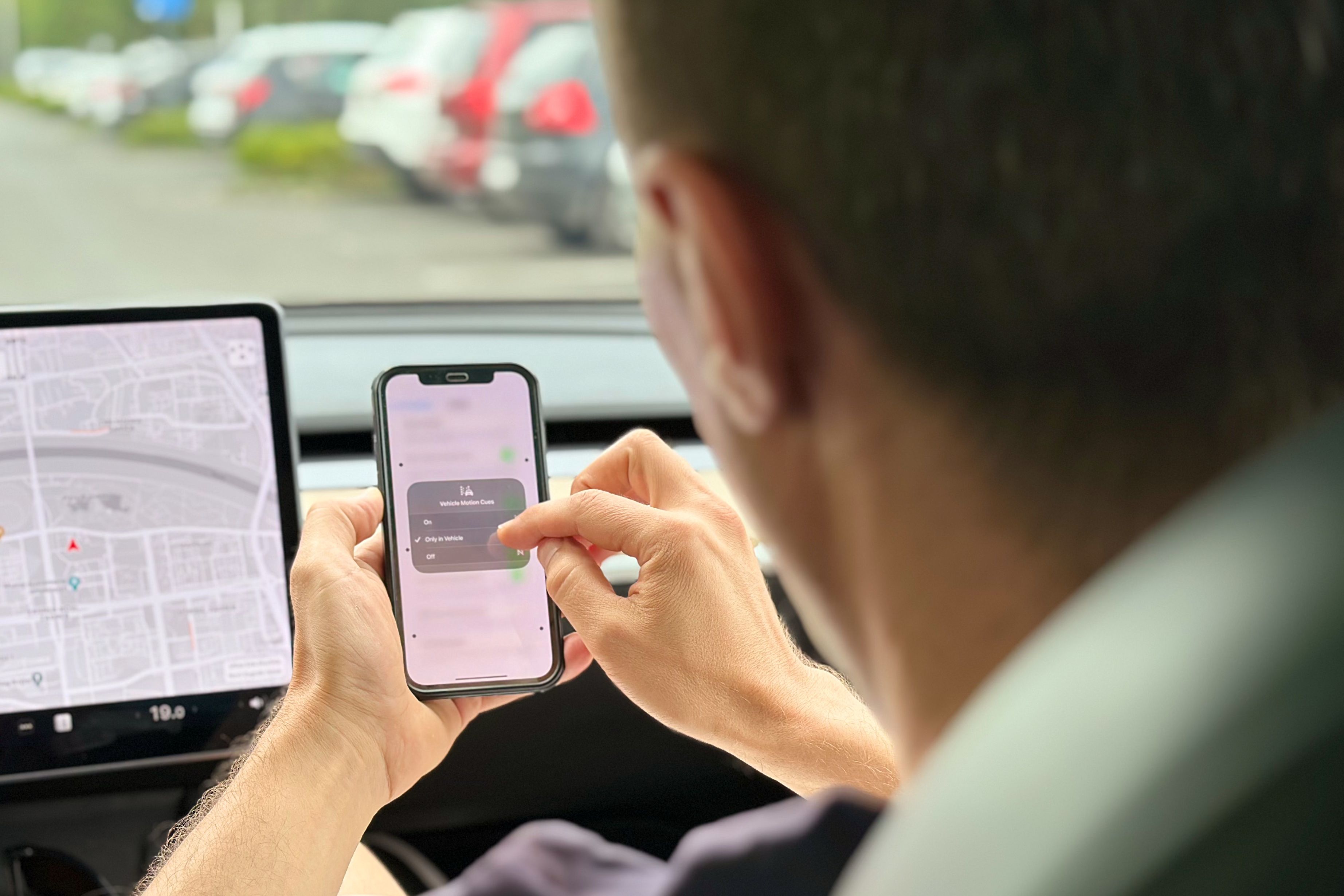 A Tesla passenger enabling Vehicle Motion Cues in their iPhone's Control Center.