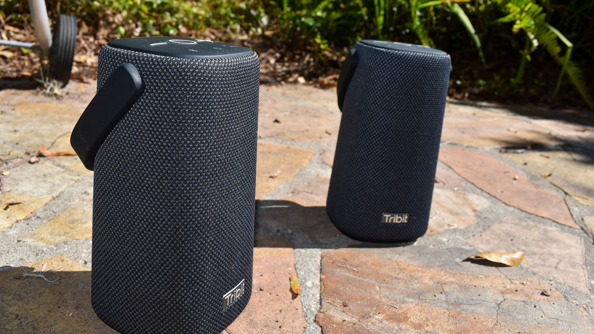 Two Tribit Stormbox Pro speakers outside on a rock patio