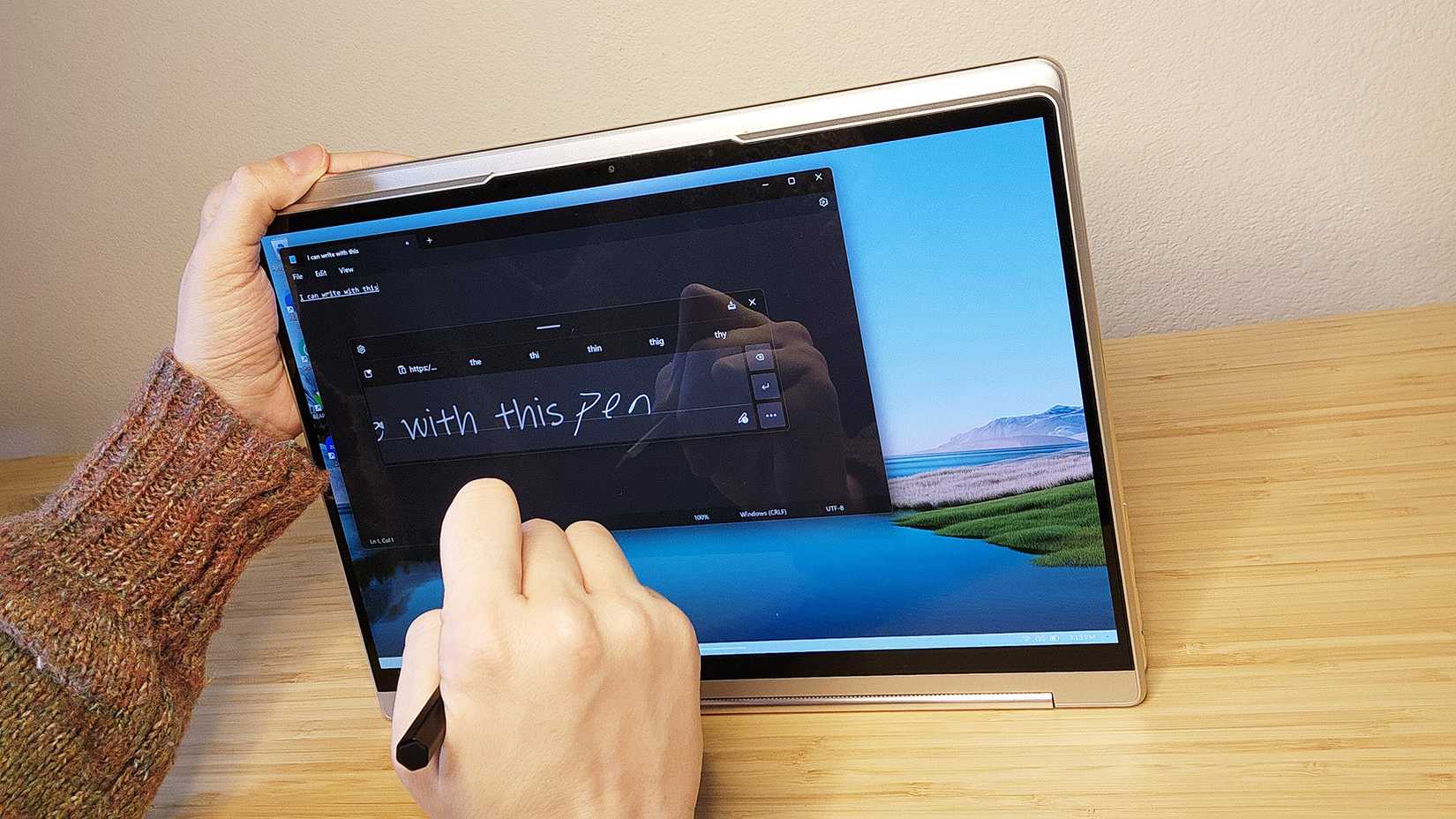 Person writing on the Lenovo Yoga 9i Gen 8 laptop screen with the included stylus.