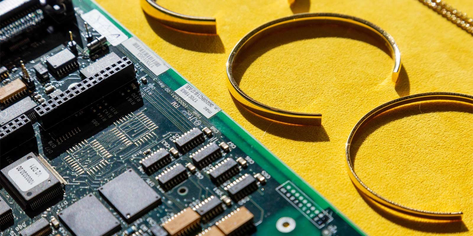 A circuit board next to some gold jewelry.