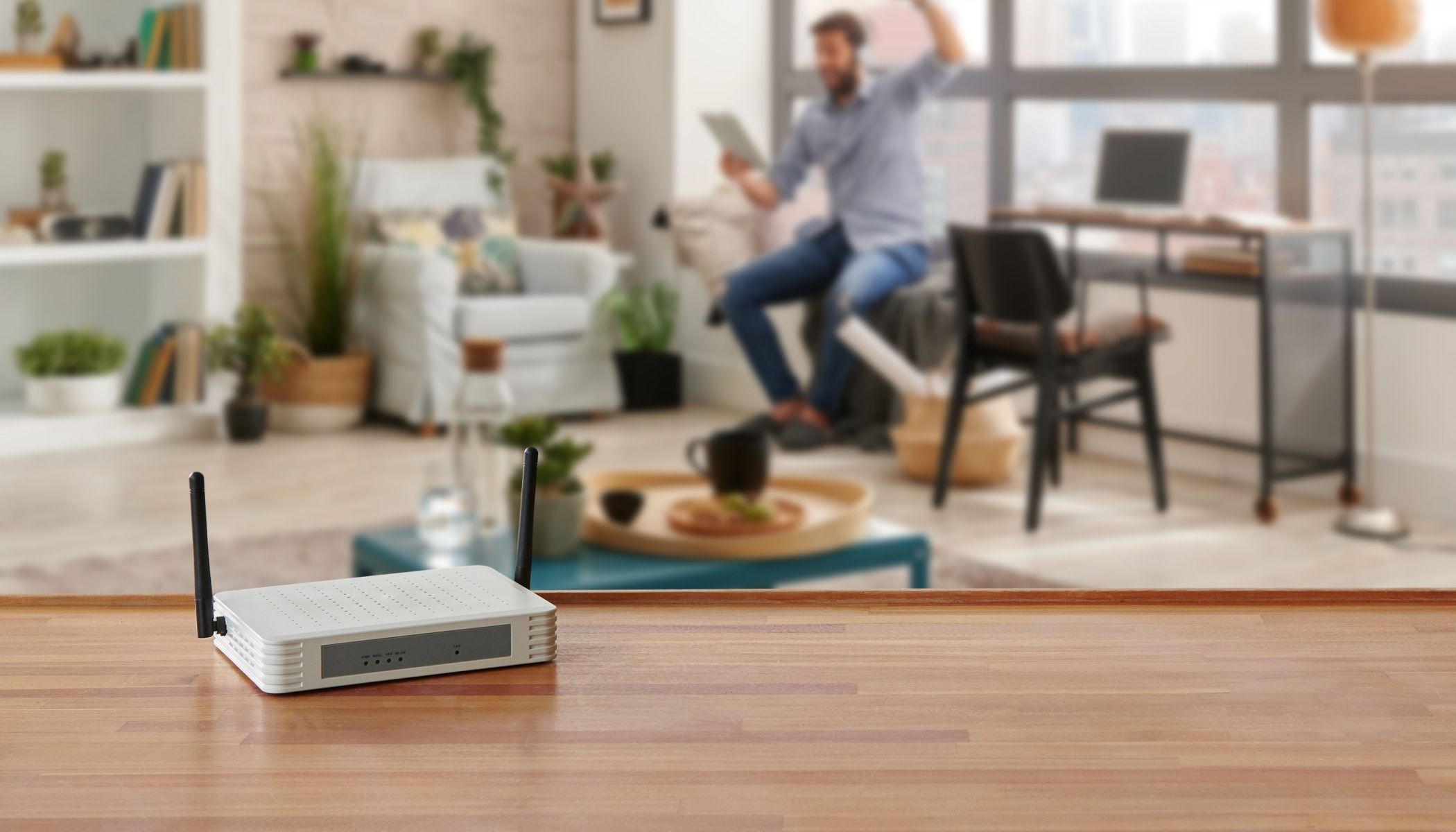 A small router on a table in the foreground with a man in the back, blurred.