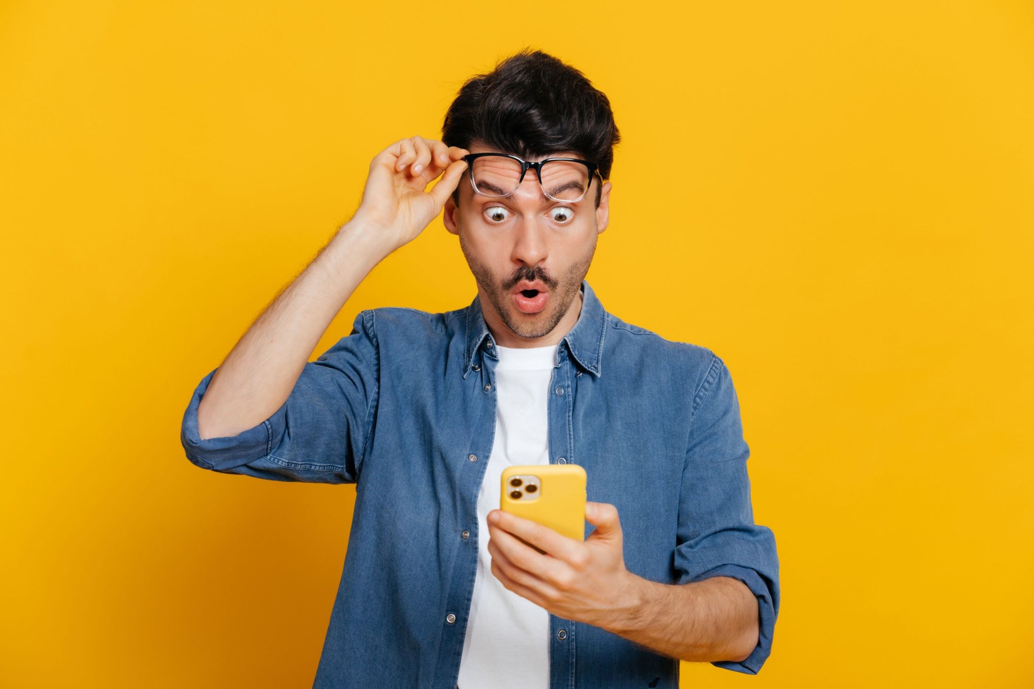 Amazed shocked caucasian guy holding smartphone in his hand