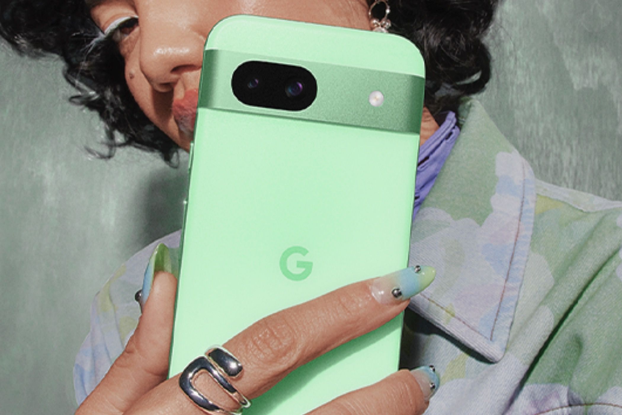 A woman holding a Aloe-colored Google Pixel 8a