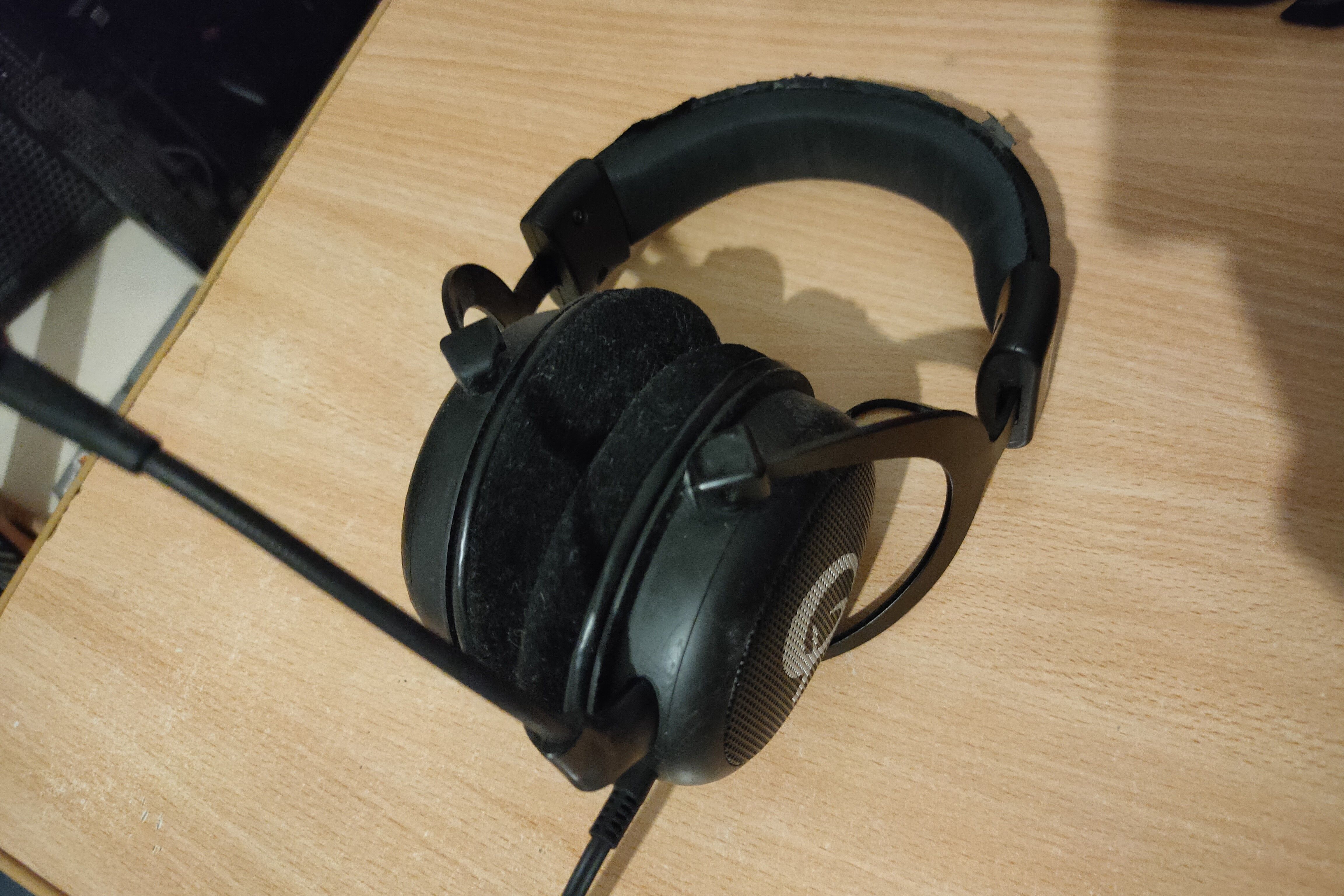 A pair of QPAD QH-85 headphones with velour ear pads sitting on a desk.