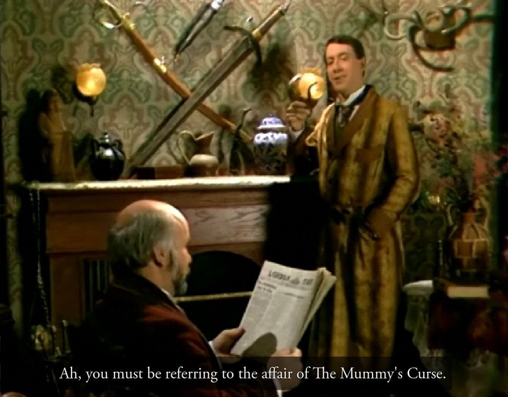 Sherlock Holmes talks to Watson in front of his fireplace.