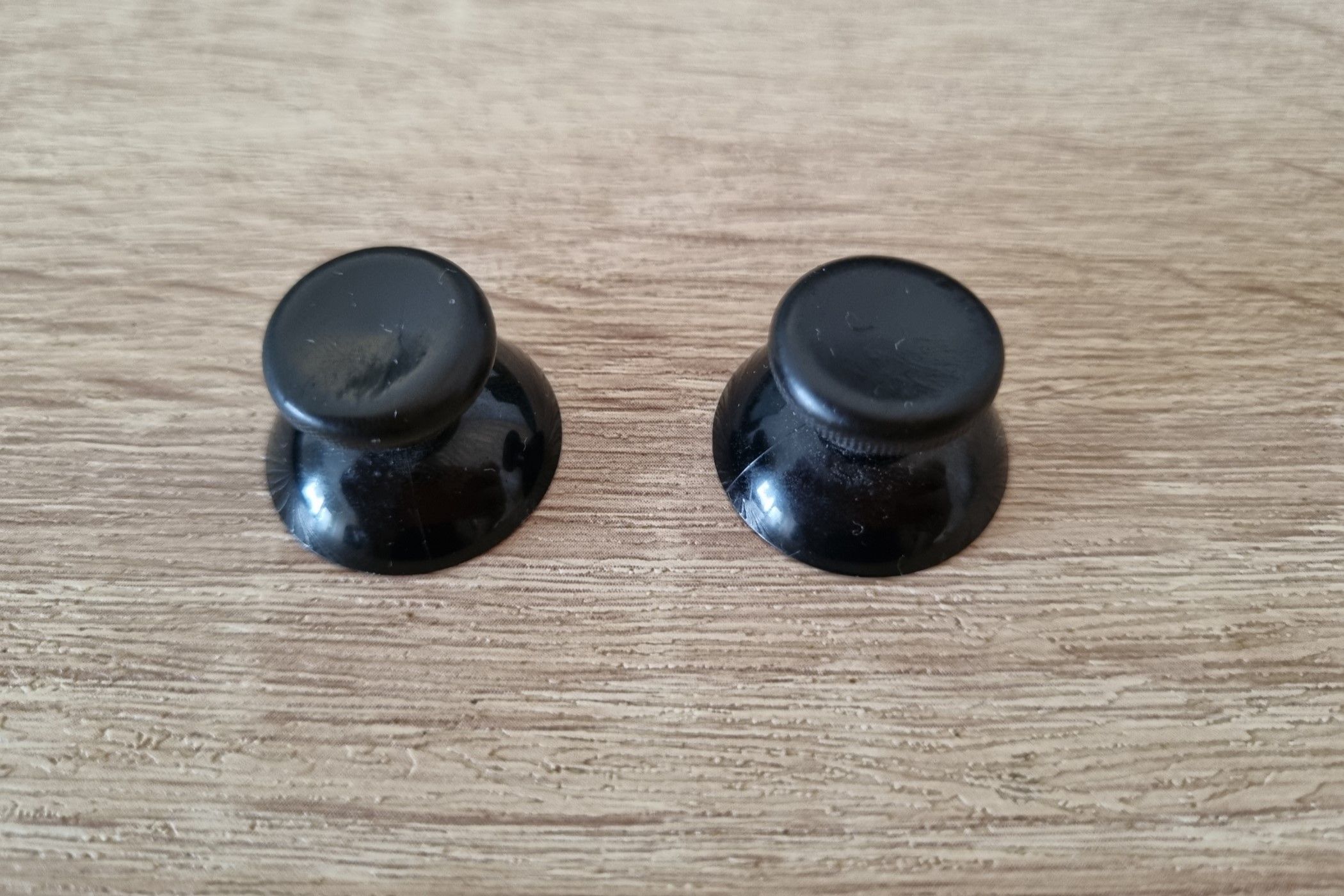 A pair of thumbsticks with degraded rubber covering the plastic body. 