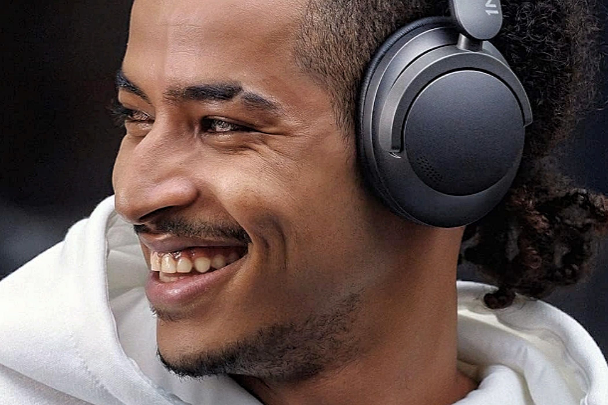 A smiling man wearing 1More Sonoflow headphones.