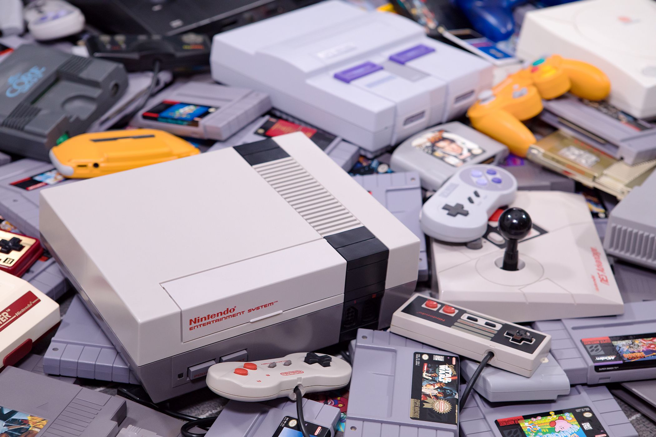 A NES and SNES console with retro game cartridges and controllers nearby.