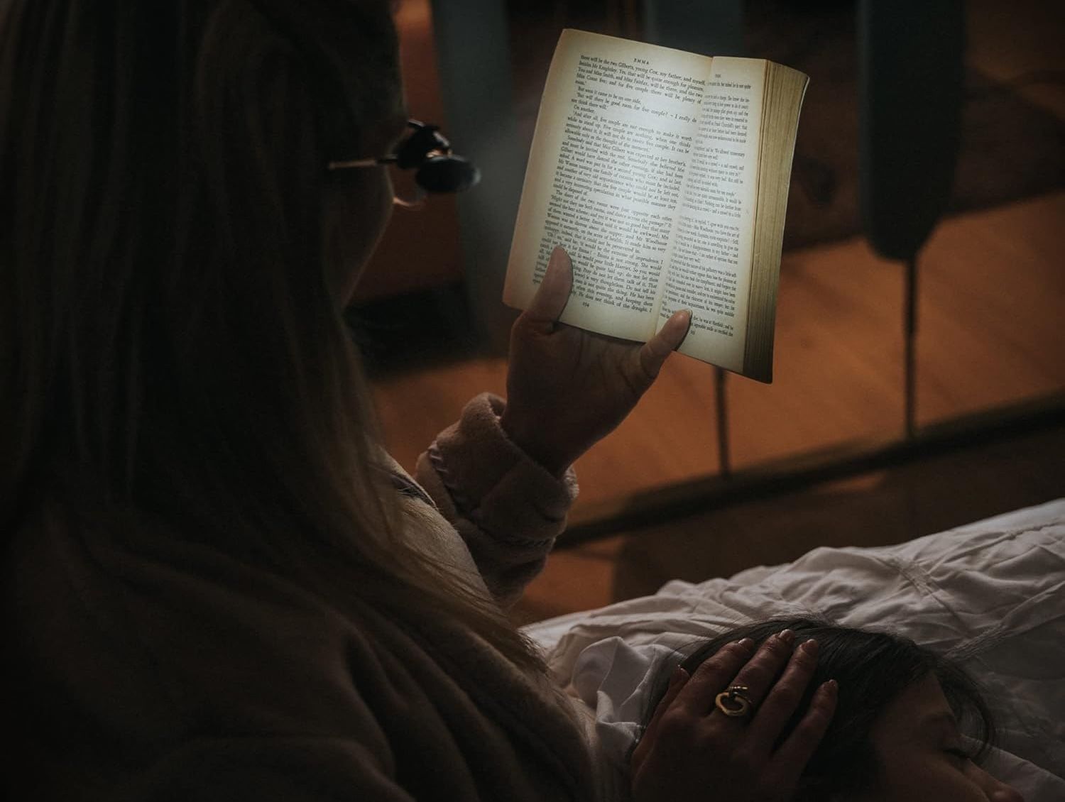 A woman wearing a clip on light to read a book