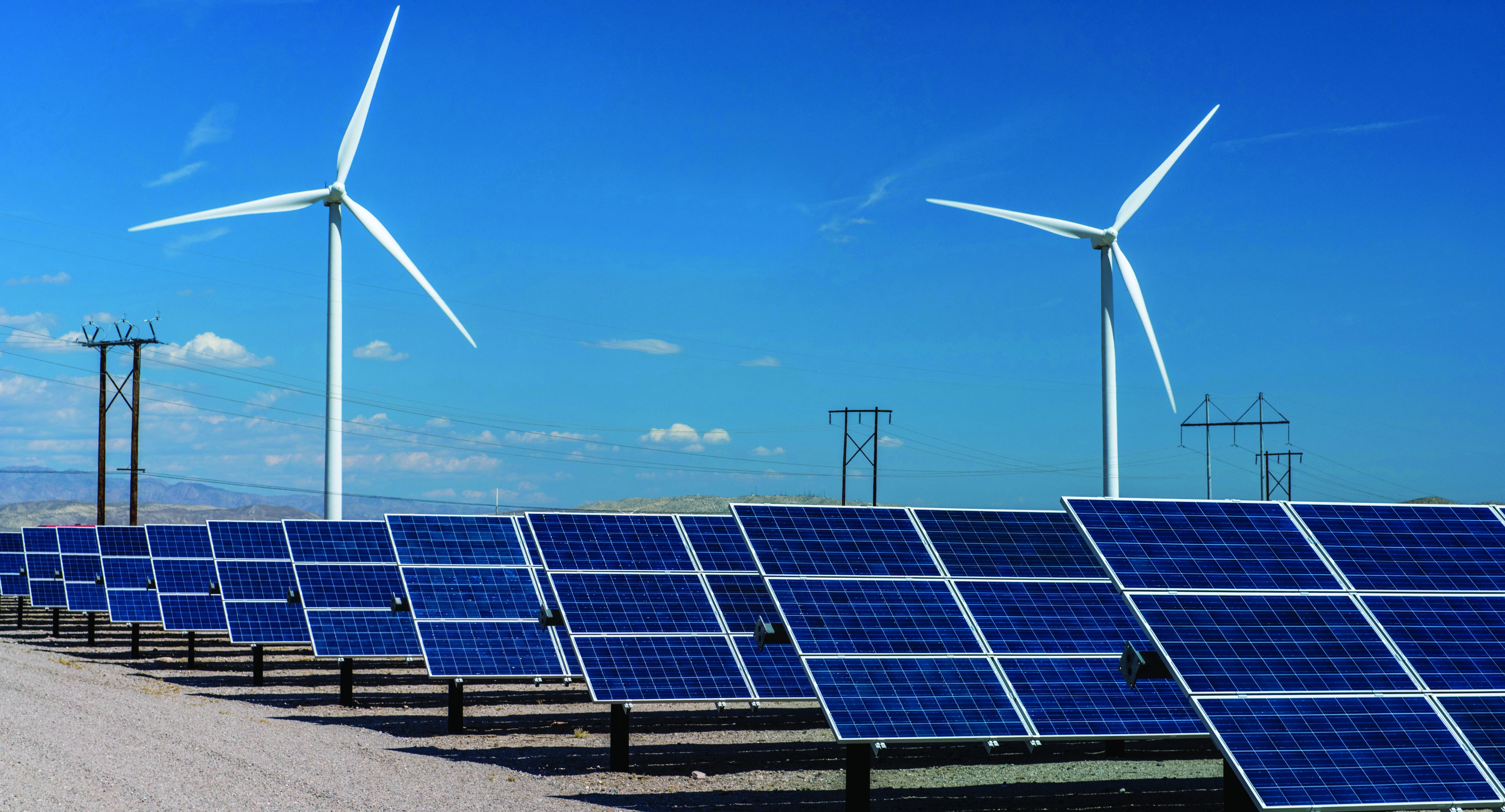 A picture of a solar farm with windmills and power lines in the background