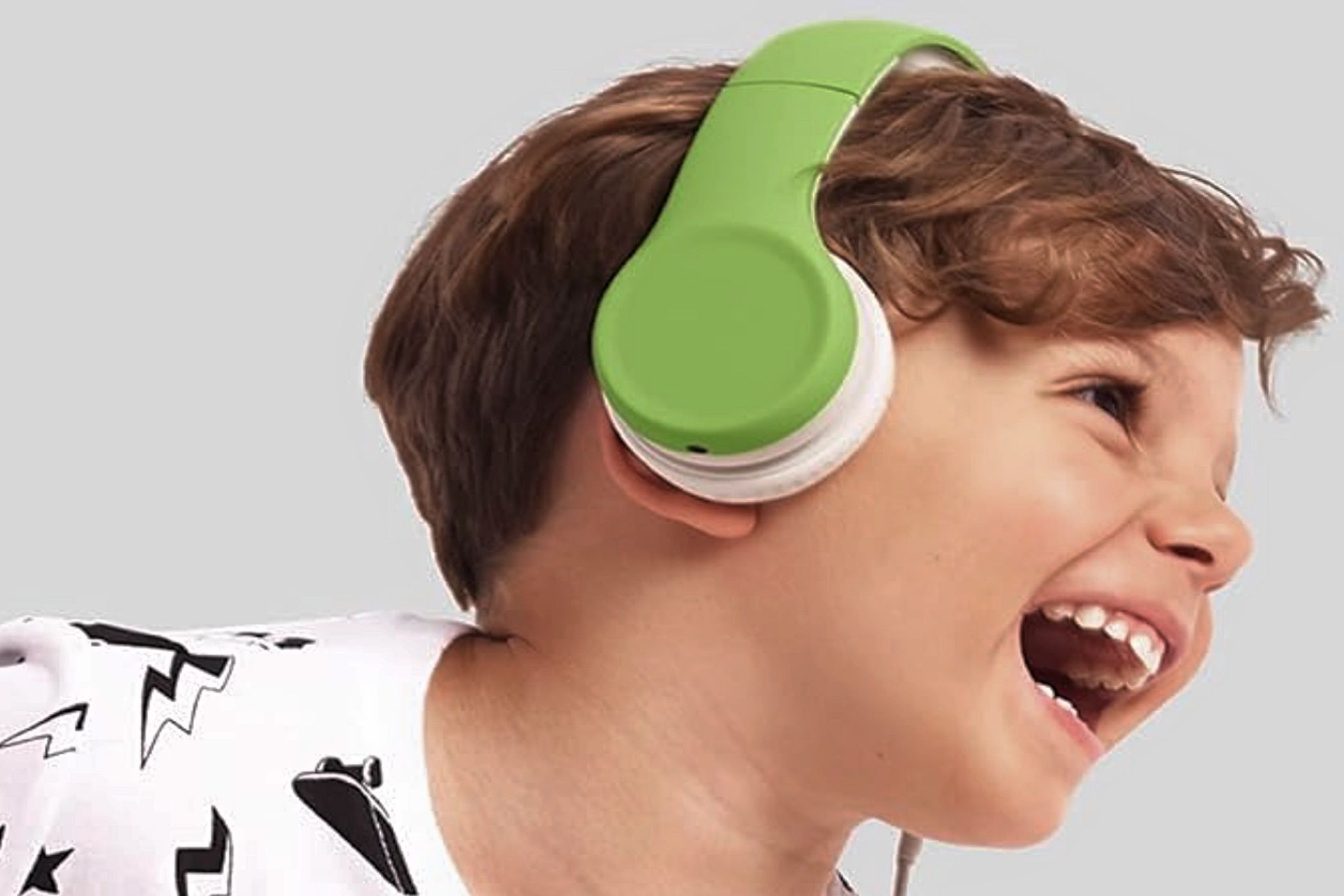 A little boy wearing a bright green set of LilGadgets Connect+ kids' headphones.