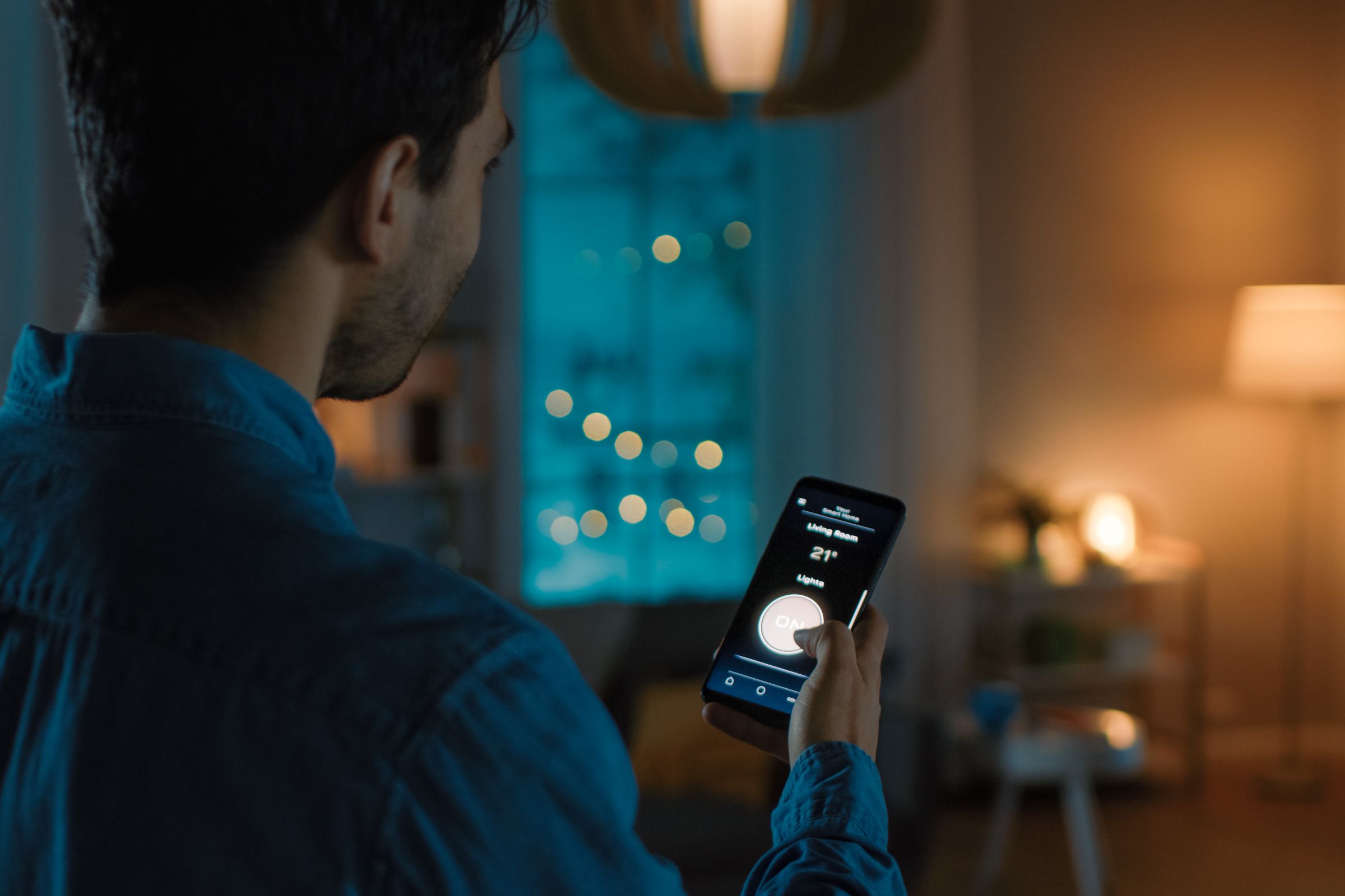 Man using smartphone to control smart home accessories.