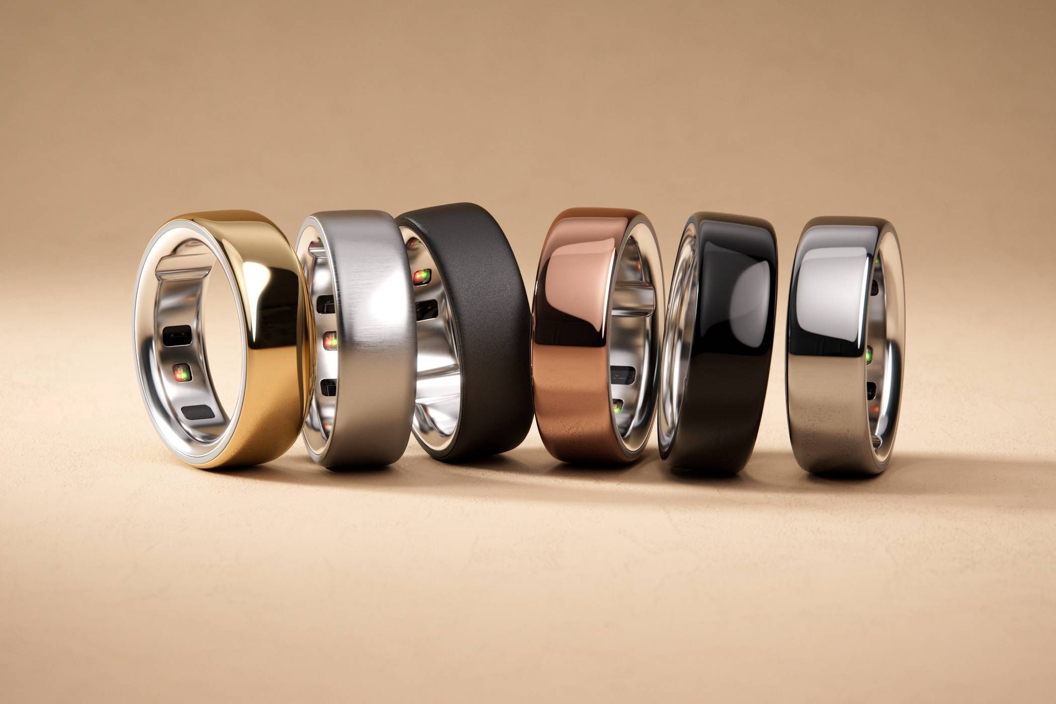 Oura Rings in a line, gold, silver black, copper, shiny black, and shinier silver from left to right