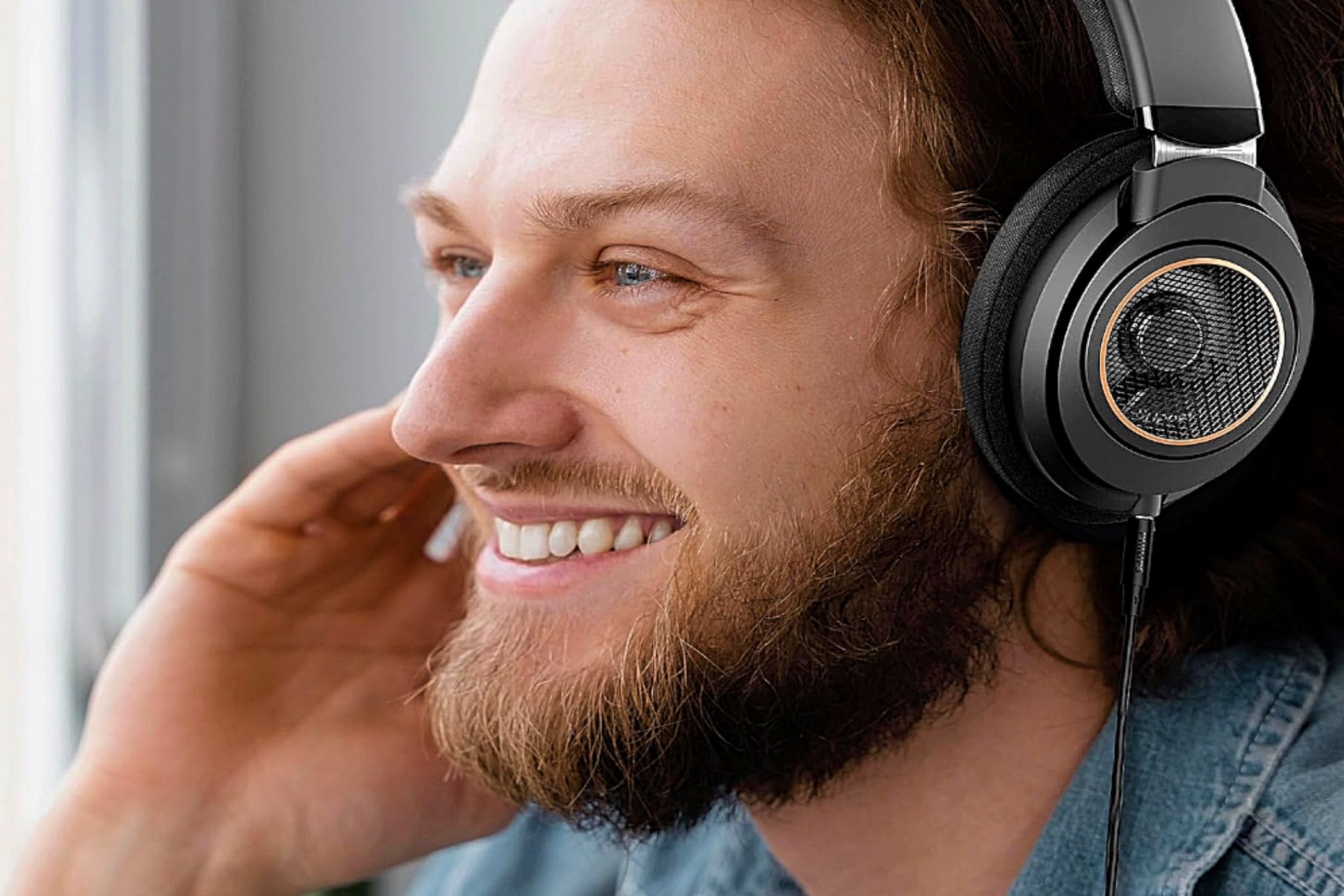 A bearded man wearing a pair of Philips Audio SHP9600 headphones.