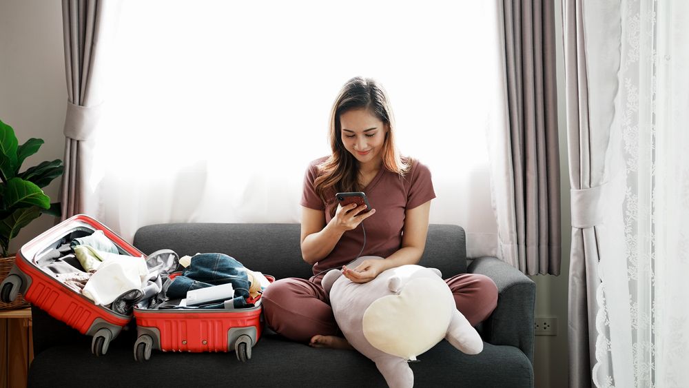 Happy woman prepares a suitcase for travel trip.