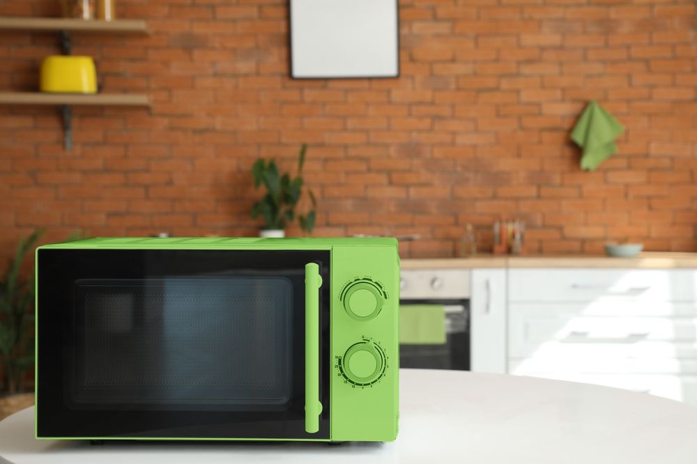 Modern green microwave oven on table in kitchen.