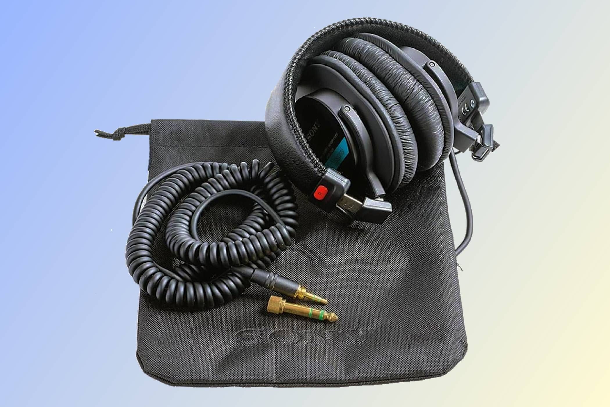 A set of Sony MDR7506 headphones with coiled cable and carry puch.