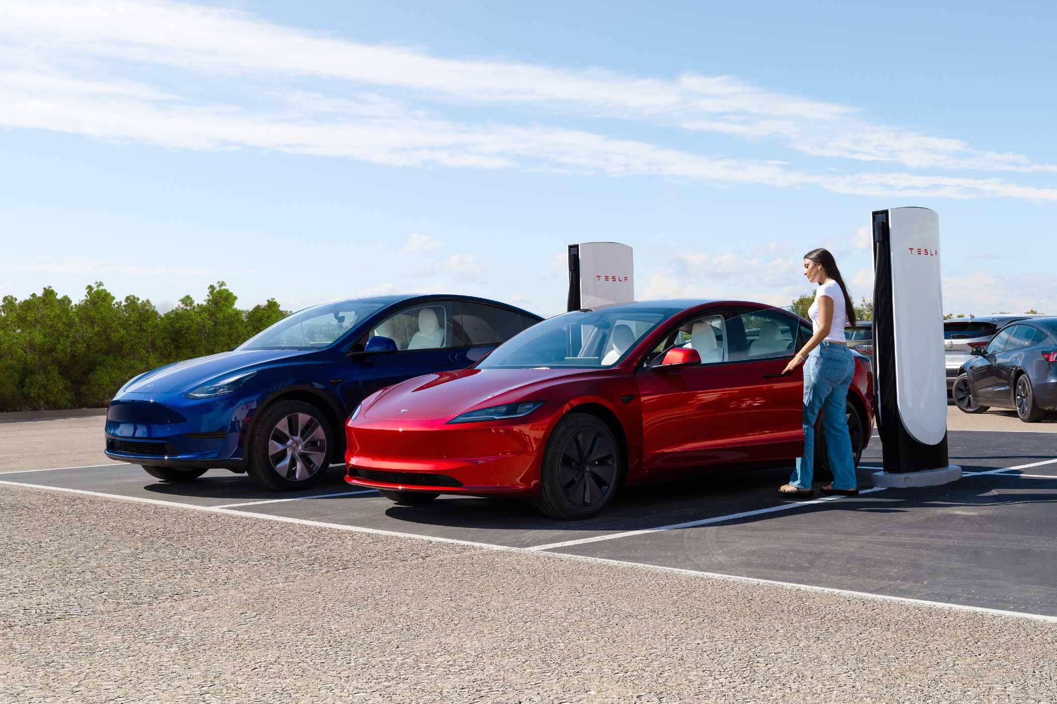 Red and blue car getting charged by a Tesla charging station