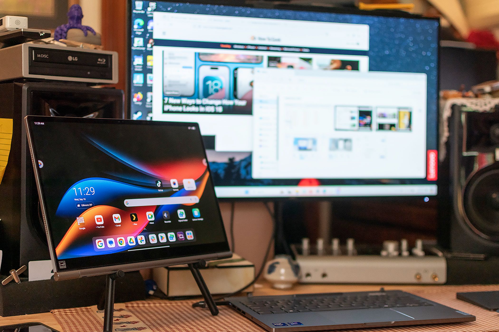 The base of the Lenovo ThinkBook Plus Gen 5 Hybrid plugged into a monitor while the detached tablet screen sits on a stand.