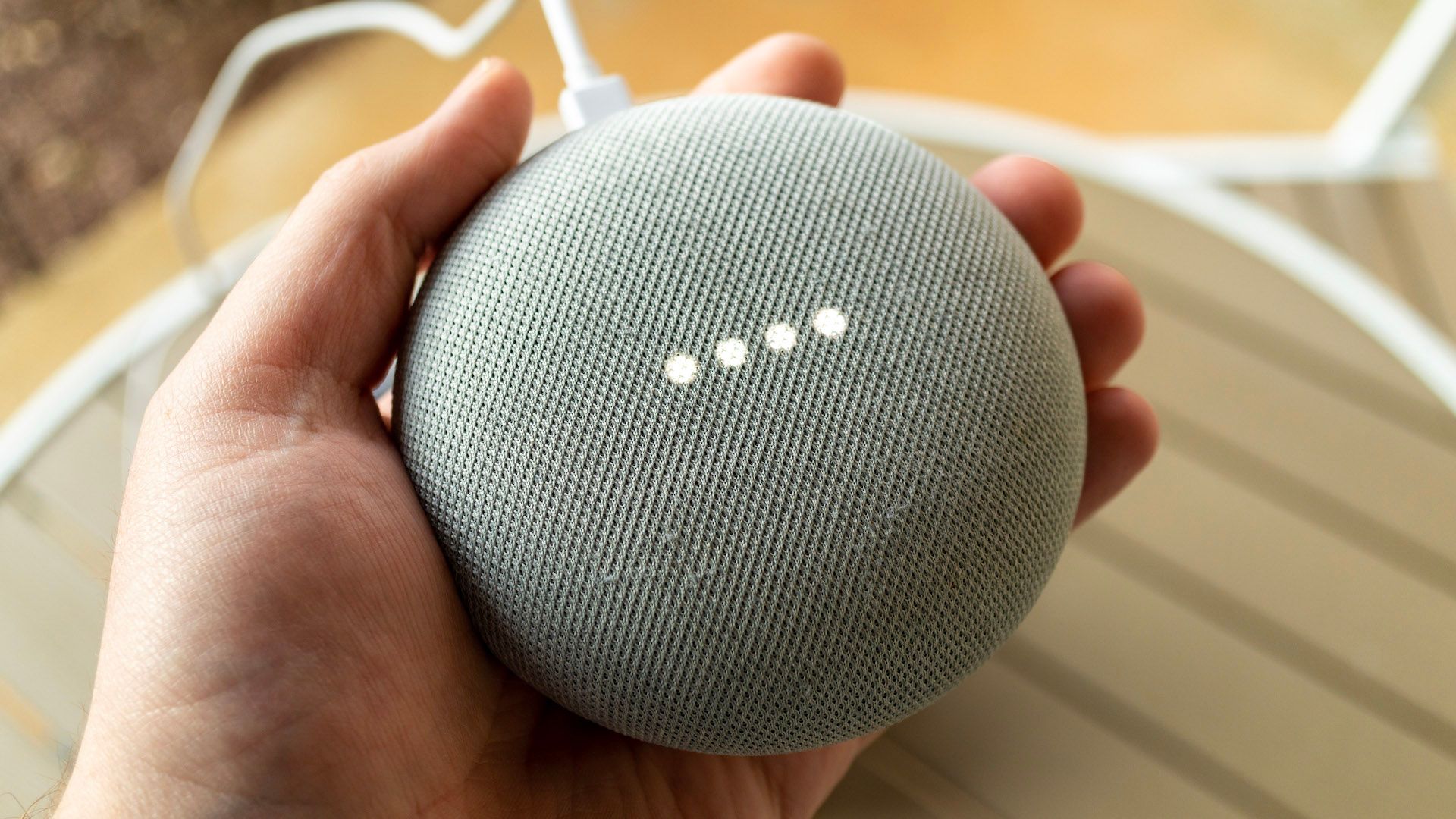 A hand holding a Google Nest speaker.