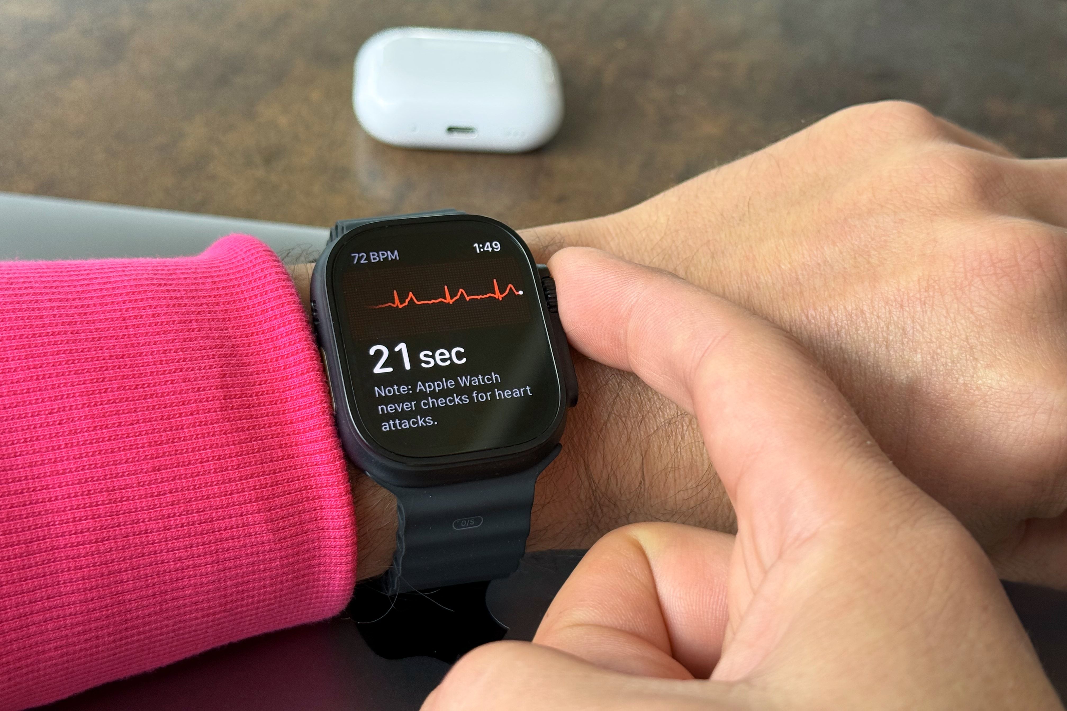 Apple Watch Ultra on a person's wrist, with the ECG app running and the index finger resting on the Digital Crown.