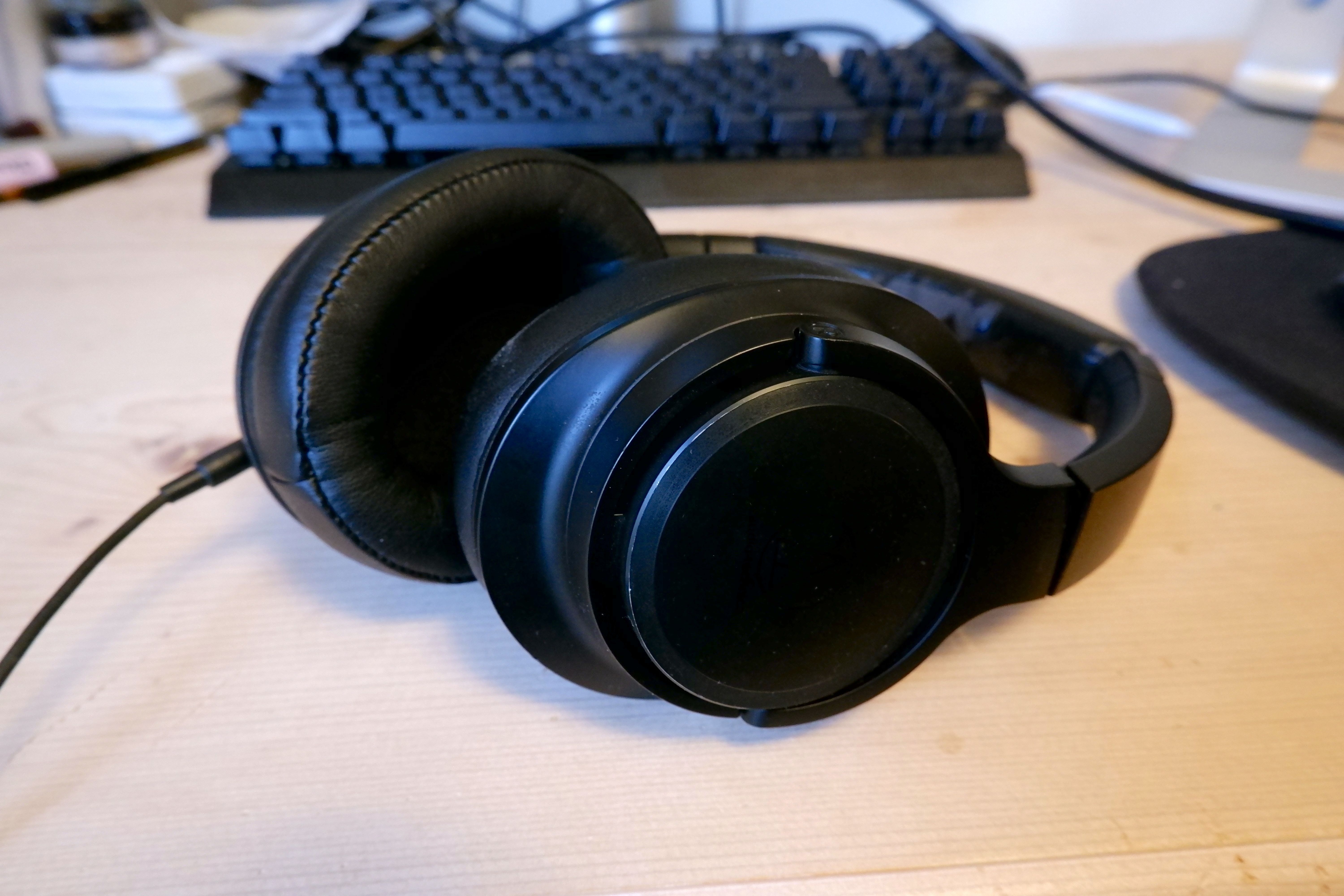 A pair of Audio-Technica ATH-SR50 headphones on a wooden desk with a keyboard in the background.